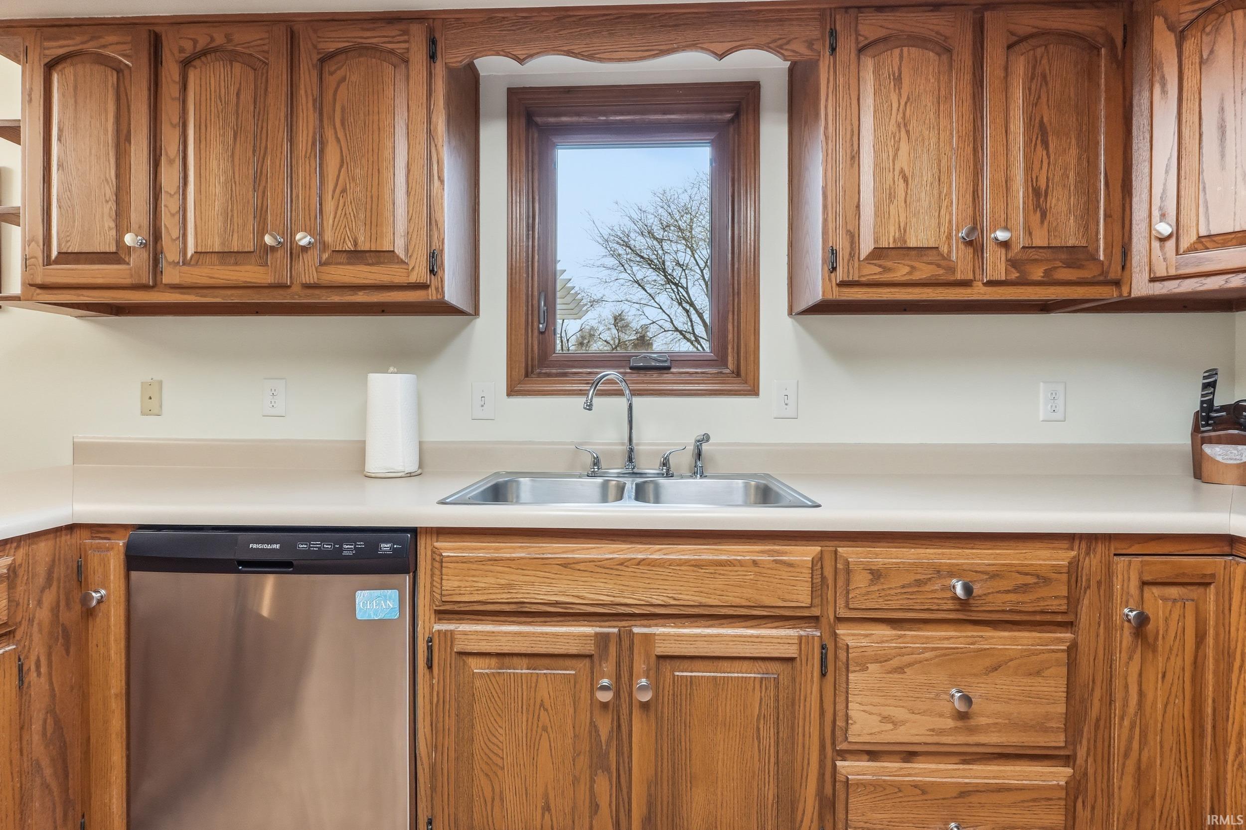 Kitchen featuring brown cabinetry, stainless steel dishwasher, and light countertops