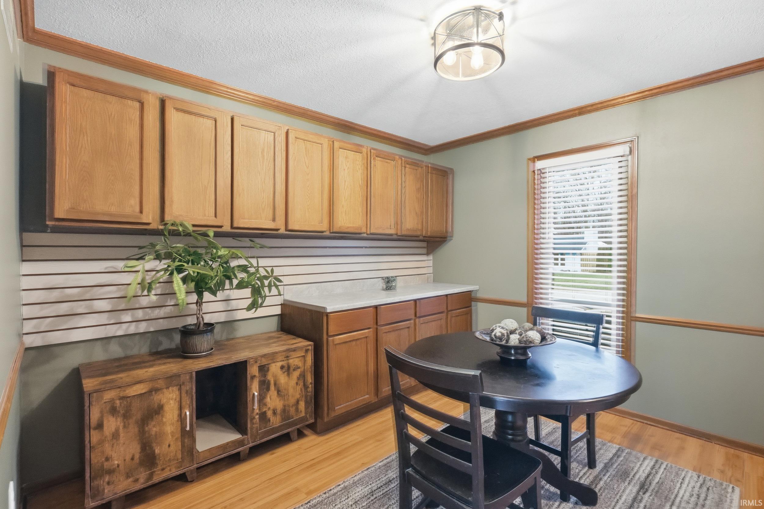 Kitchen featuring ornamental molding, light countertops, light wood-style flooring, and brown cabinetry