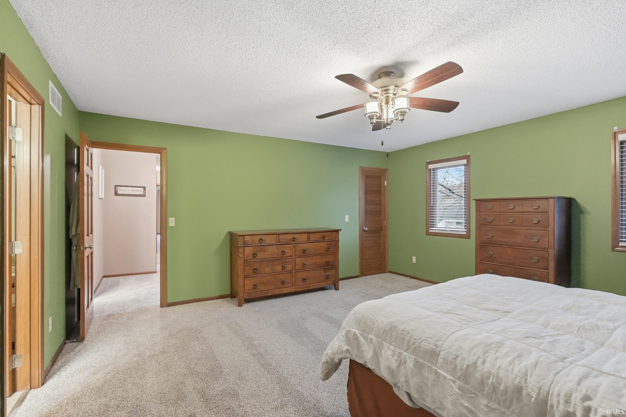 Carpeted bedroom with a textured ceiling, a ceiling fan, and a closet