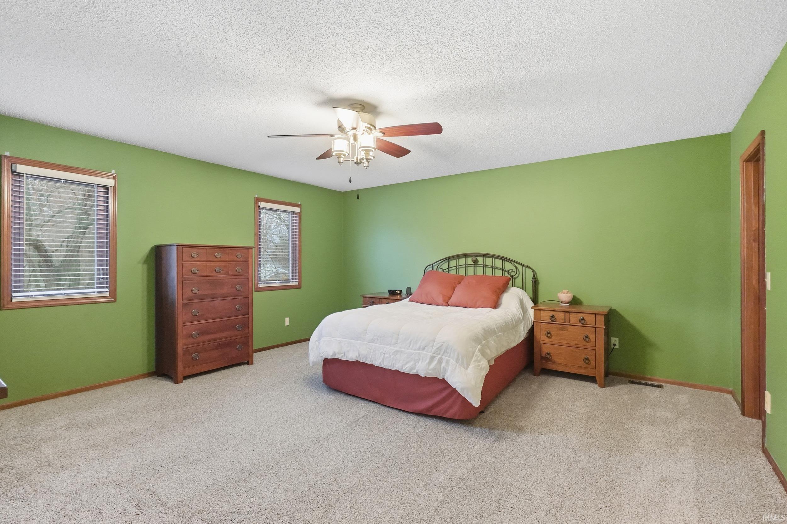 Carpeted bedroom with a textured ceiling and ceiling fan