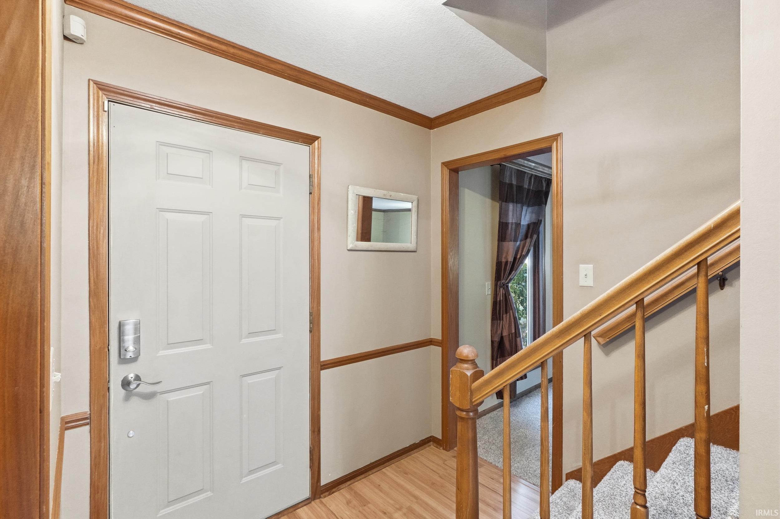Foyer entrance featuring crown molding and light wood-style floors