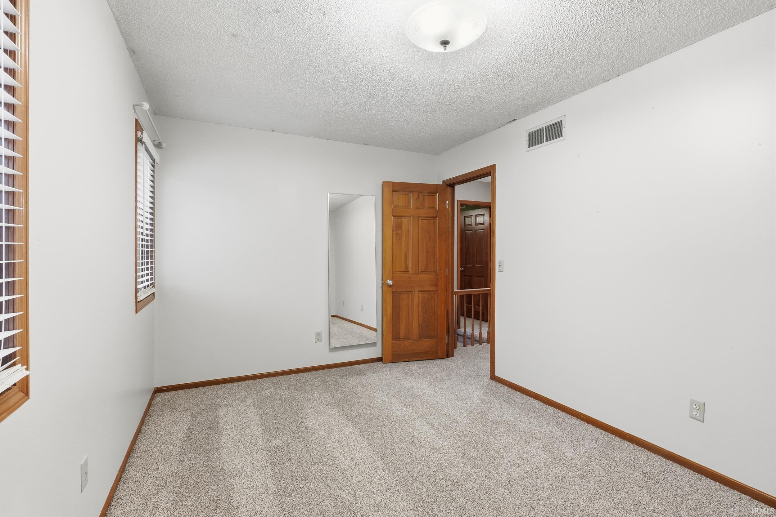 Unfurnished room featuring carpet floors and a textured ceiling