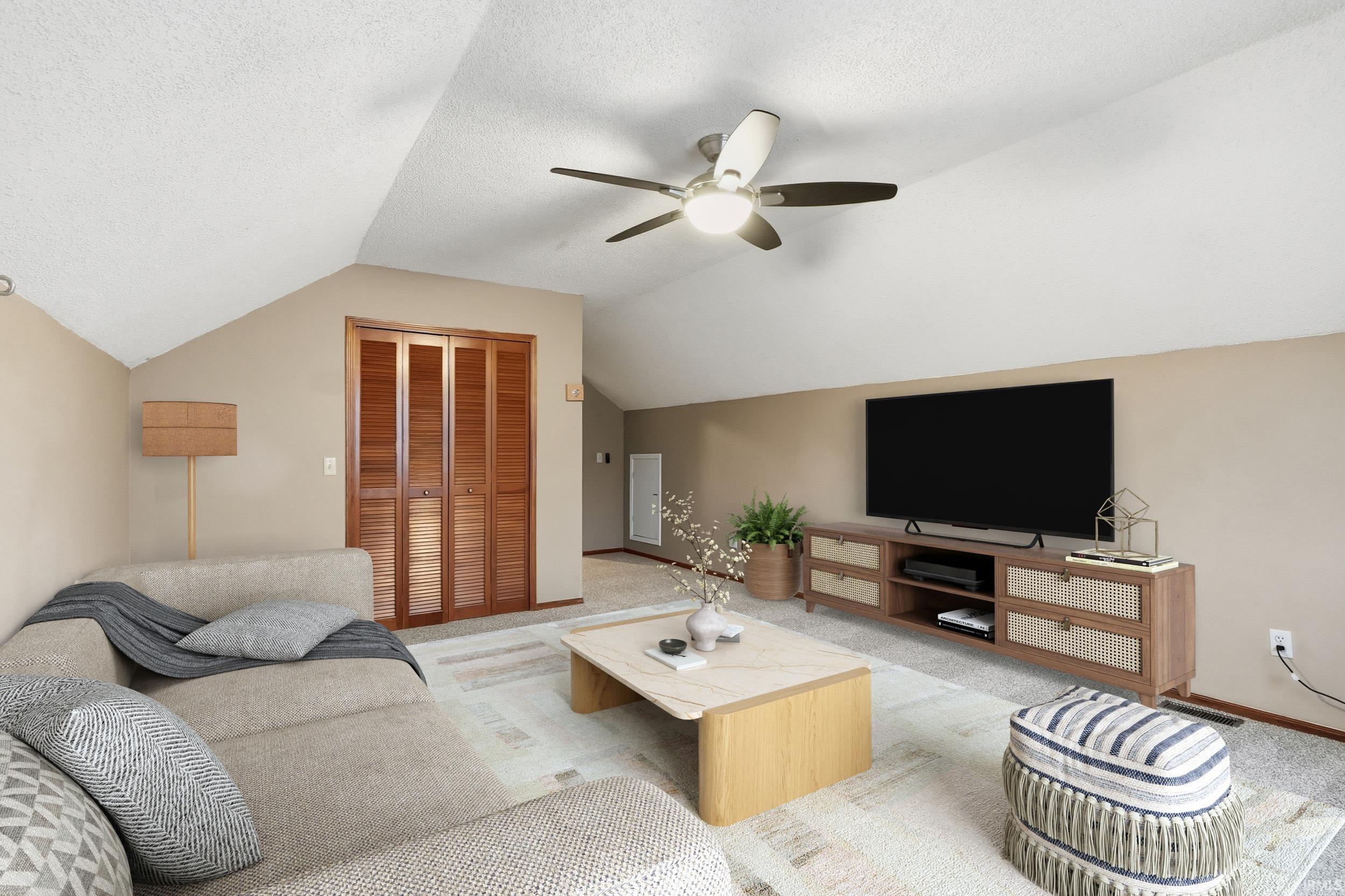 Living area with light colored carpet, lofted ceiling, a ceiling fan, and a textured ceiling