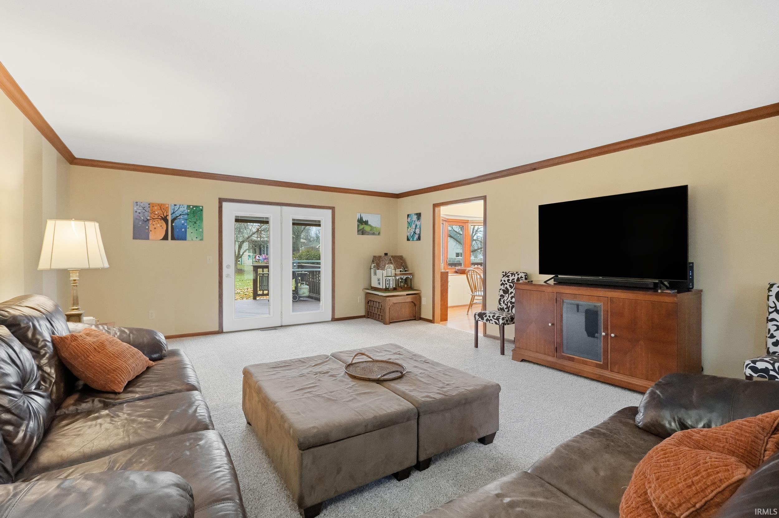 Living room featuring carpet flooring and ornamental molding