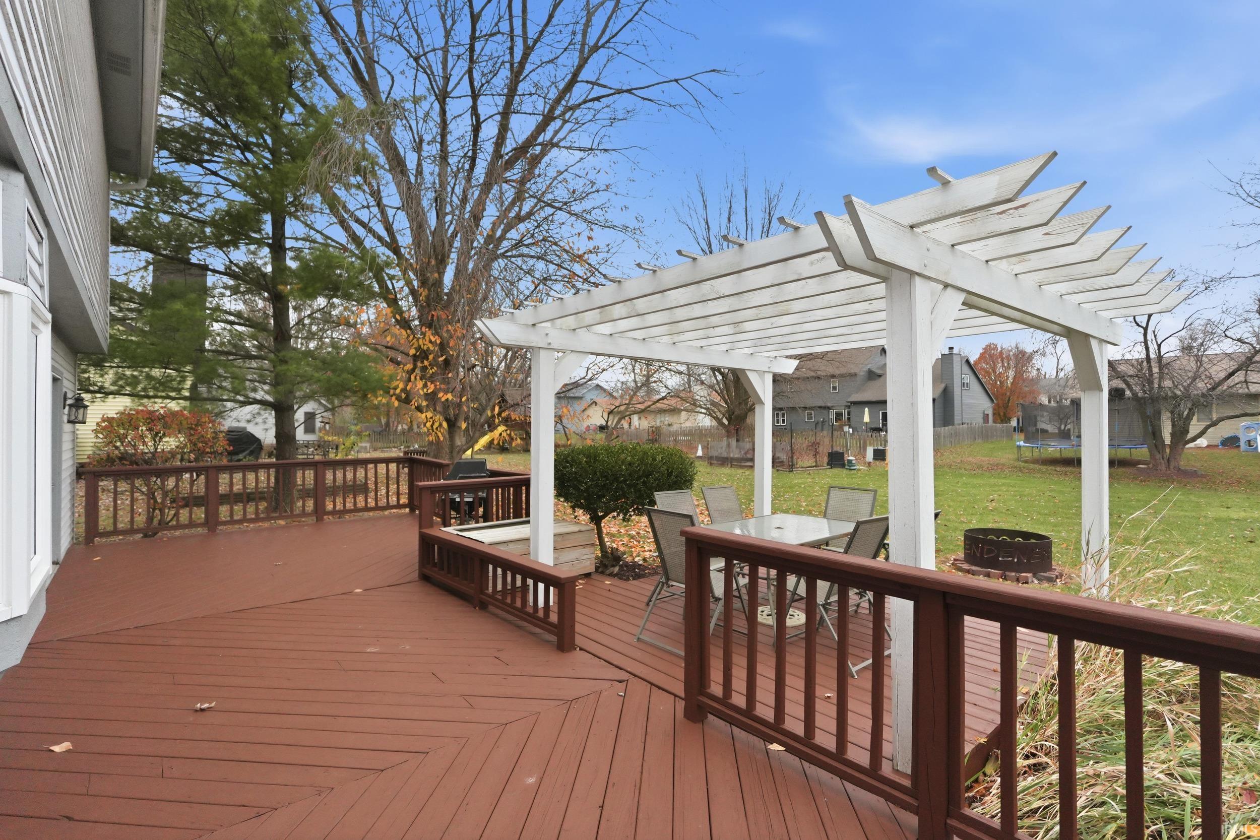 Wooden deck with a lawn, outdoor dining space, and a fire pit