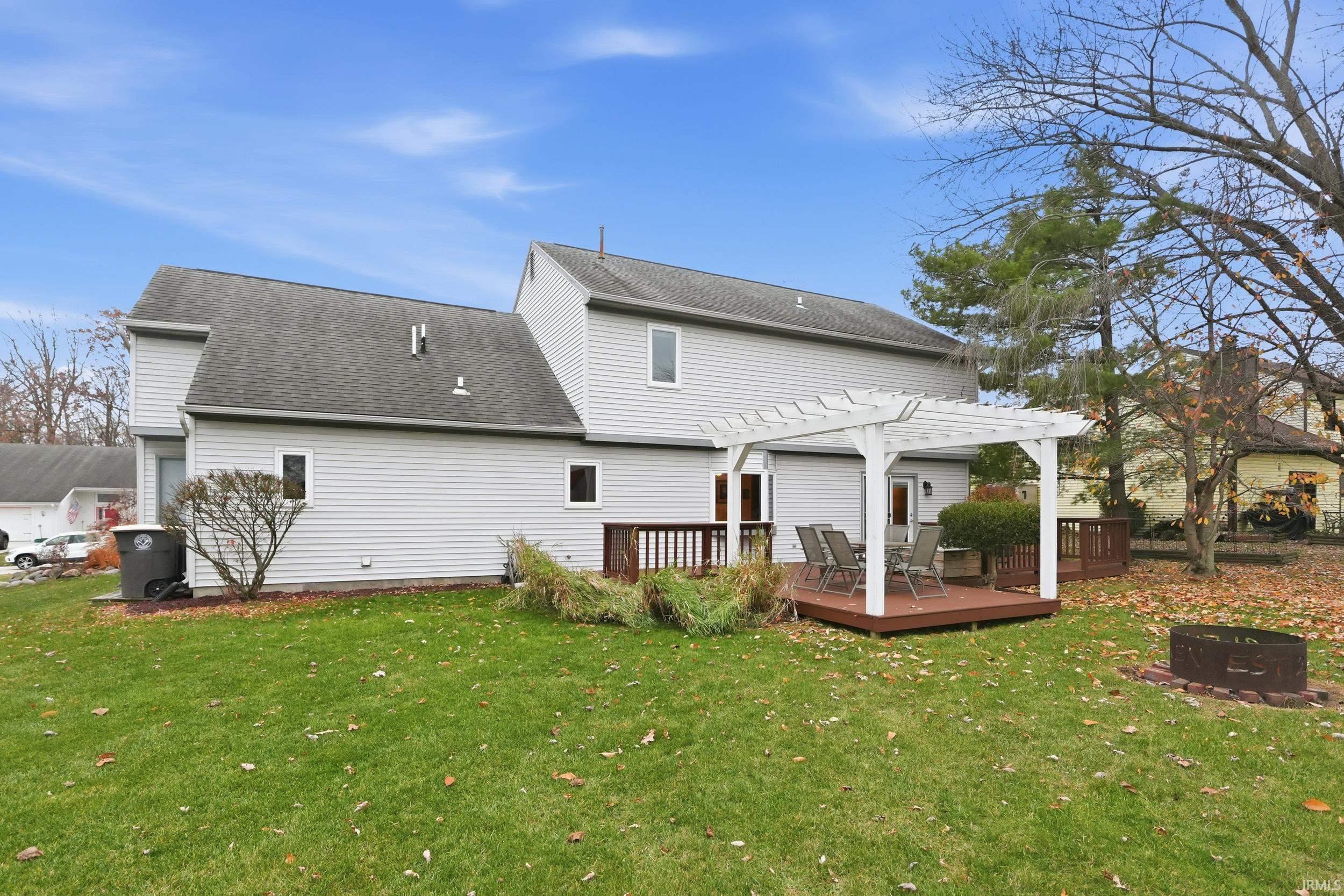 Back of property with a fire pit, a lawn, a shingled roof, and a pergola