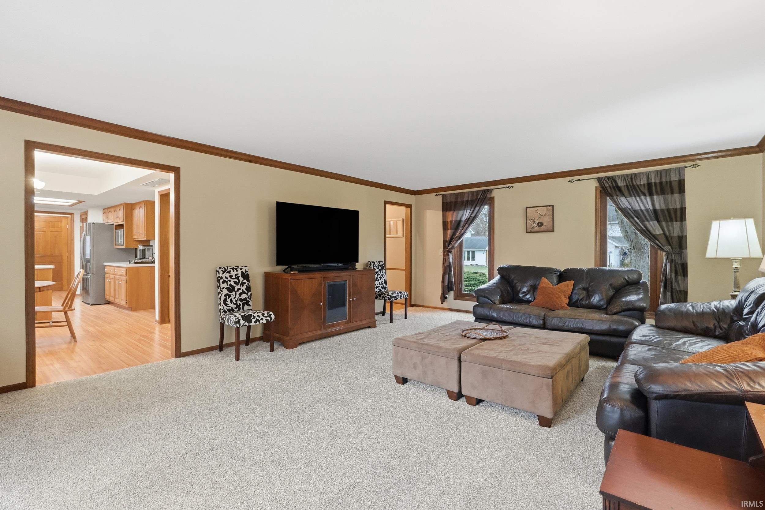 Living area featuring crown molding and light carpet