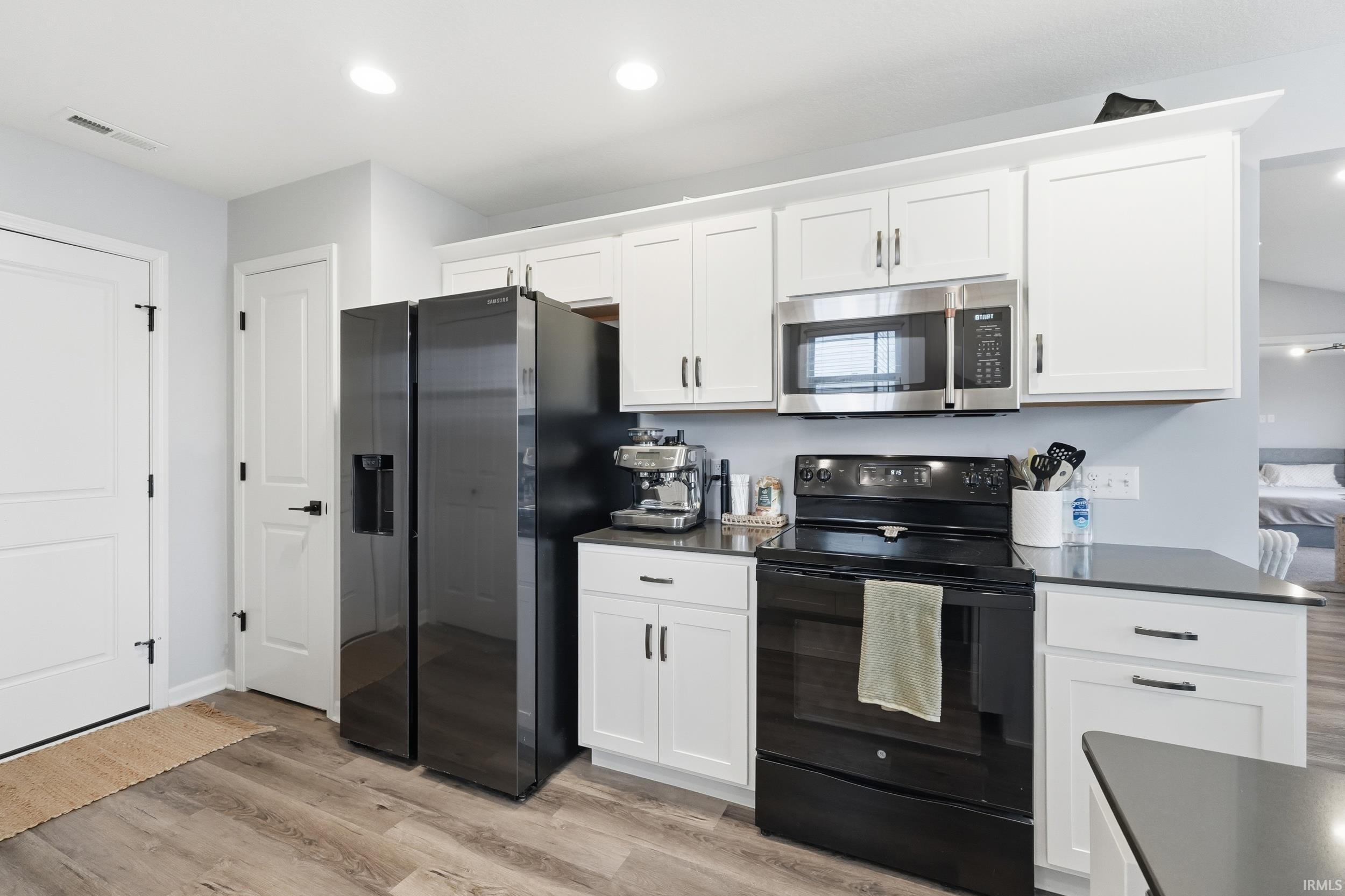 Kitchen featuring appliances with stainless steel finishes, white cabinets, light wood-type flooring, and recessed lighting