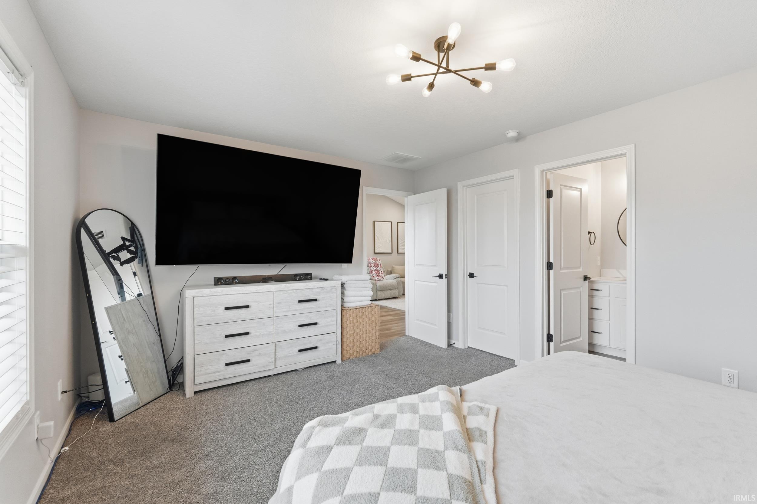 Bedroom featuring light carpet, a chandelier, and connected bathroom
