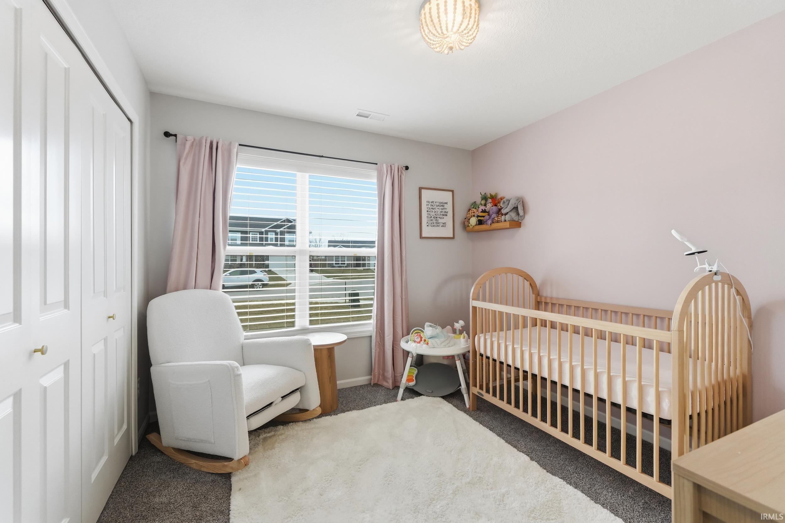 Bedroom featuring carpet flooring, a crib, and a closet