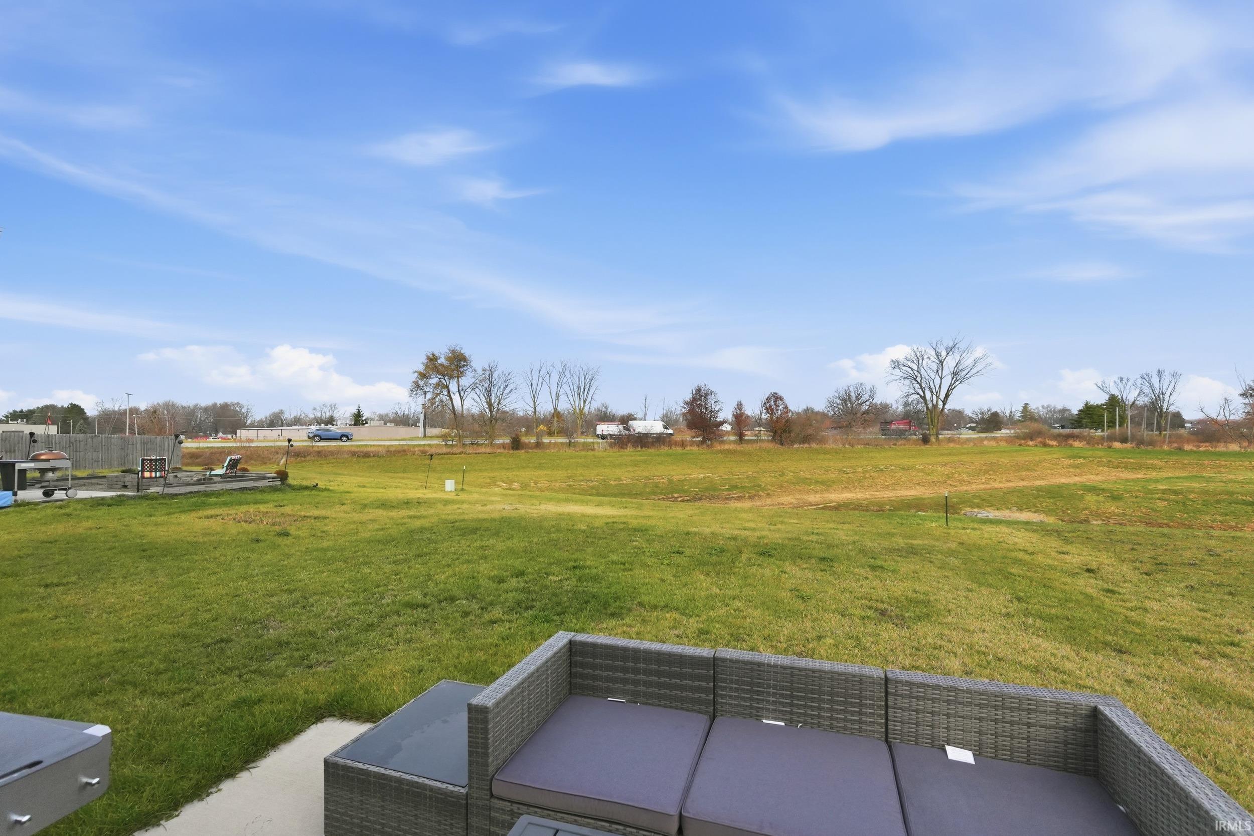 View of green lawn with a rural view and a patio area