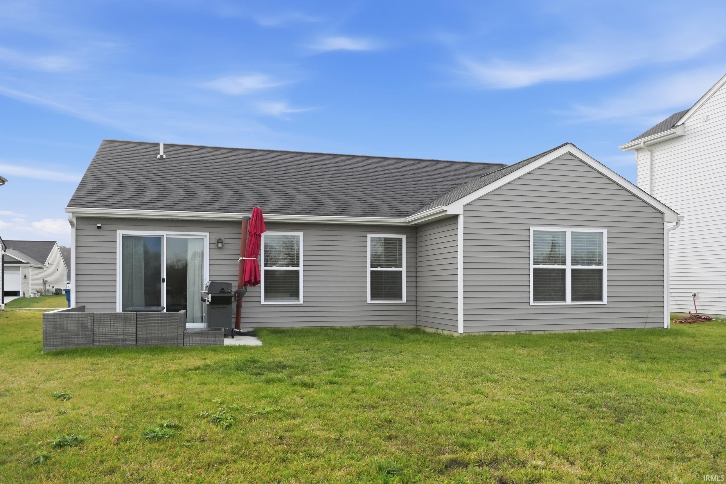 Back of property with a yard and a shingled roof