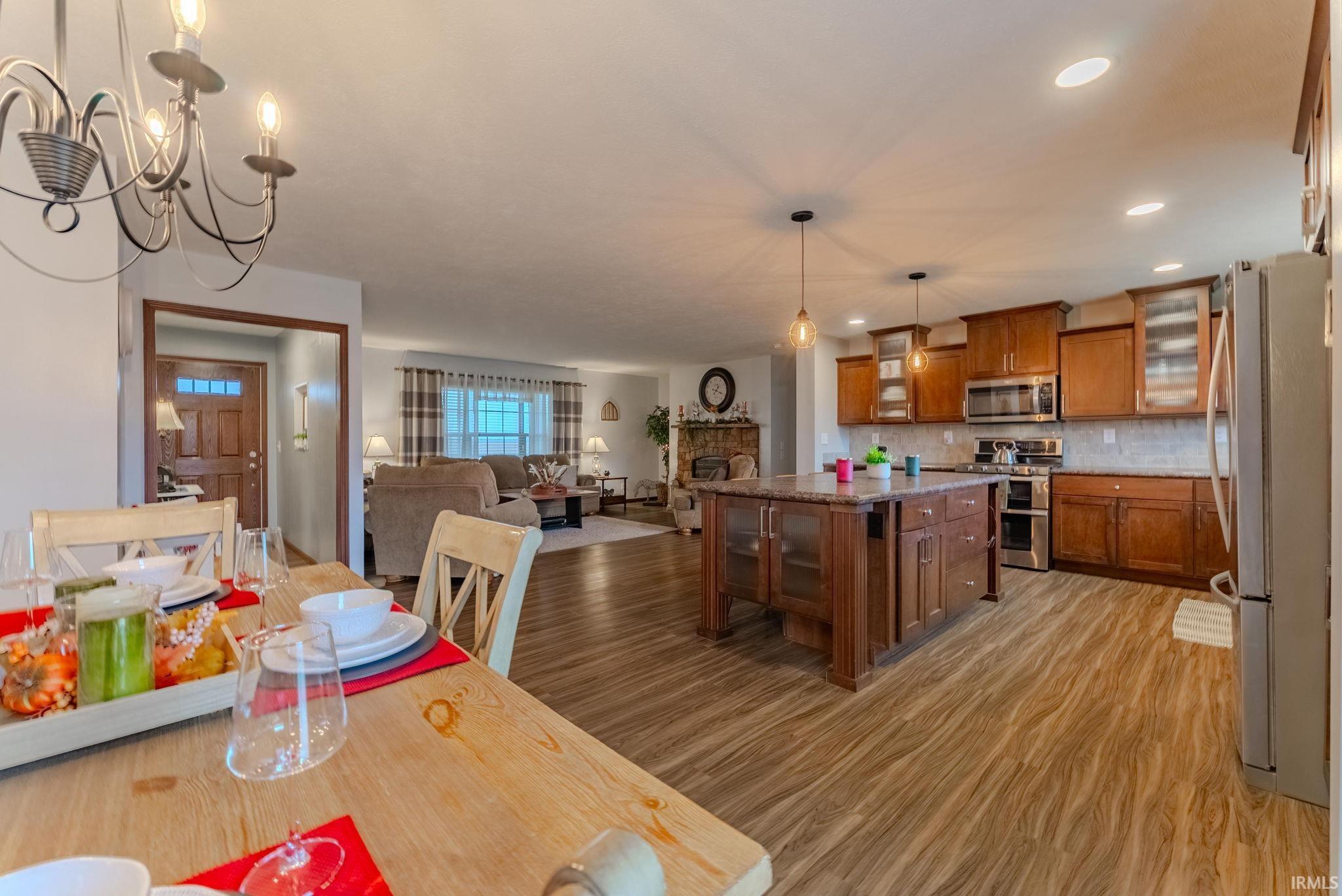 Dining space featuring a fireplace, light wood finished floors, recessed lighting, and a chandelier