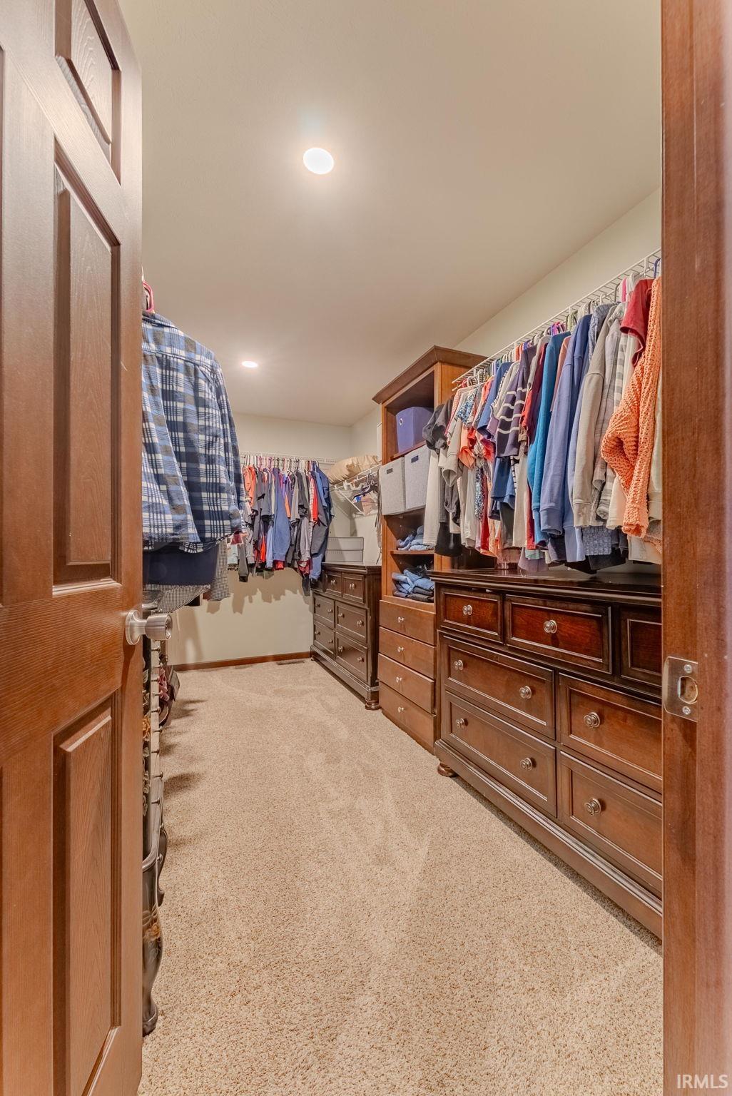 Walk in closet with light colored carpet