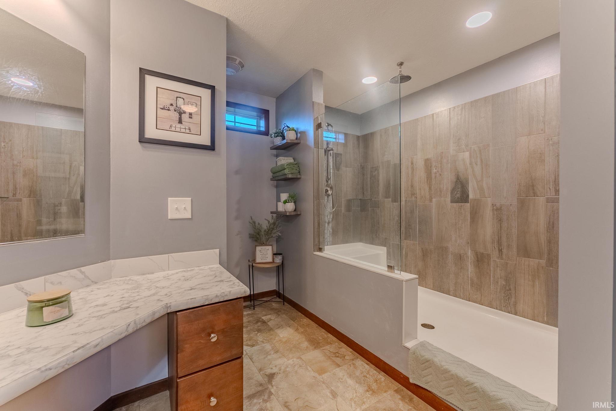 Bathroom featuring walk in shower, vanity, and recessed lighting