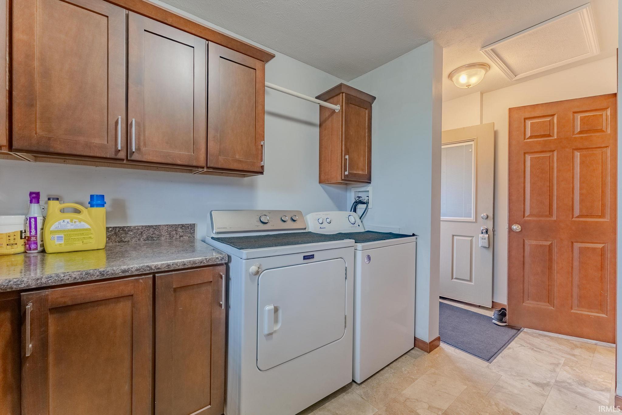 Washroom featuring cabinet space, washer and clothes dryer, and attic access