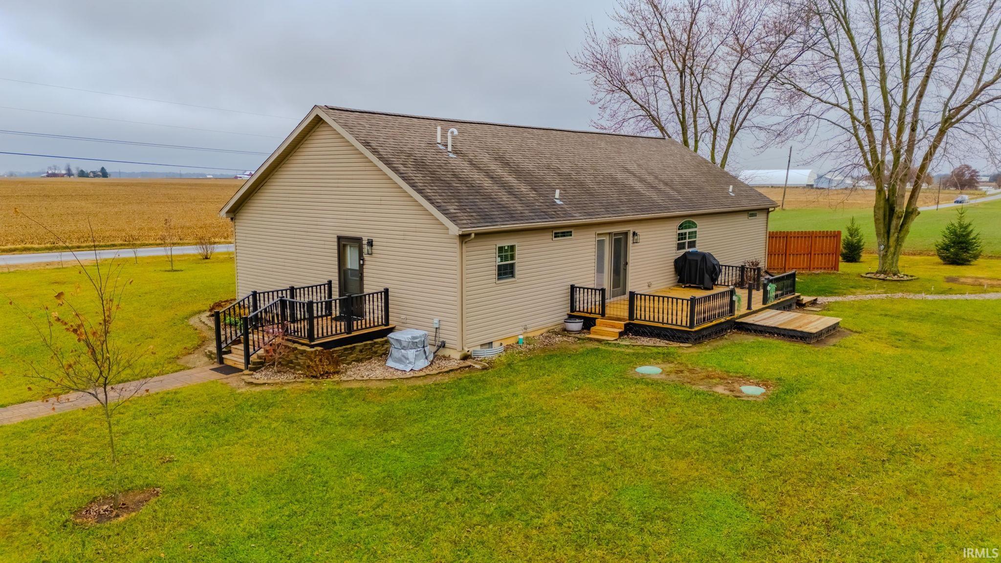 Back of house featuring a deck, a lawn, and a shingled roof