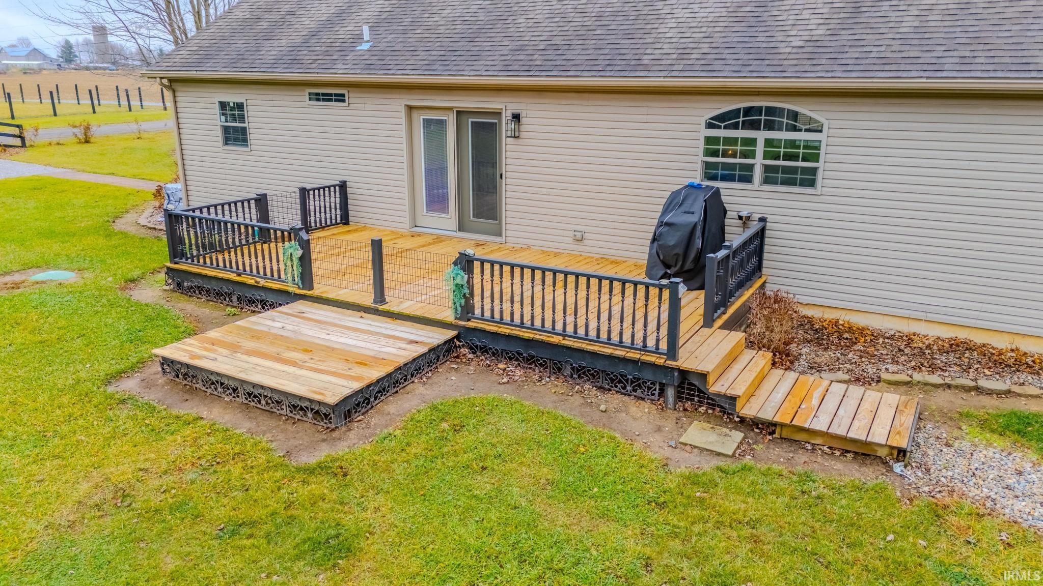 Back of house with roof with shingles, a lawn, and a wooden deck
