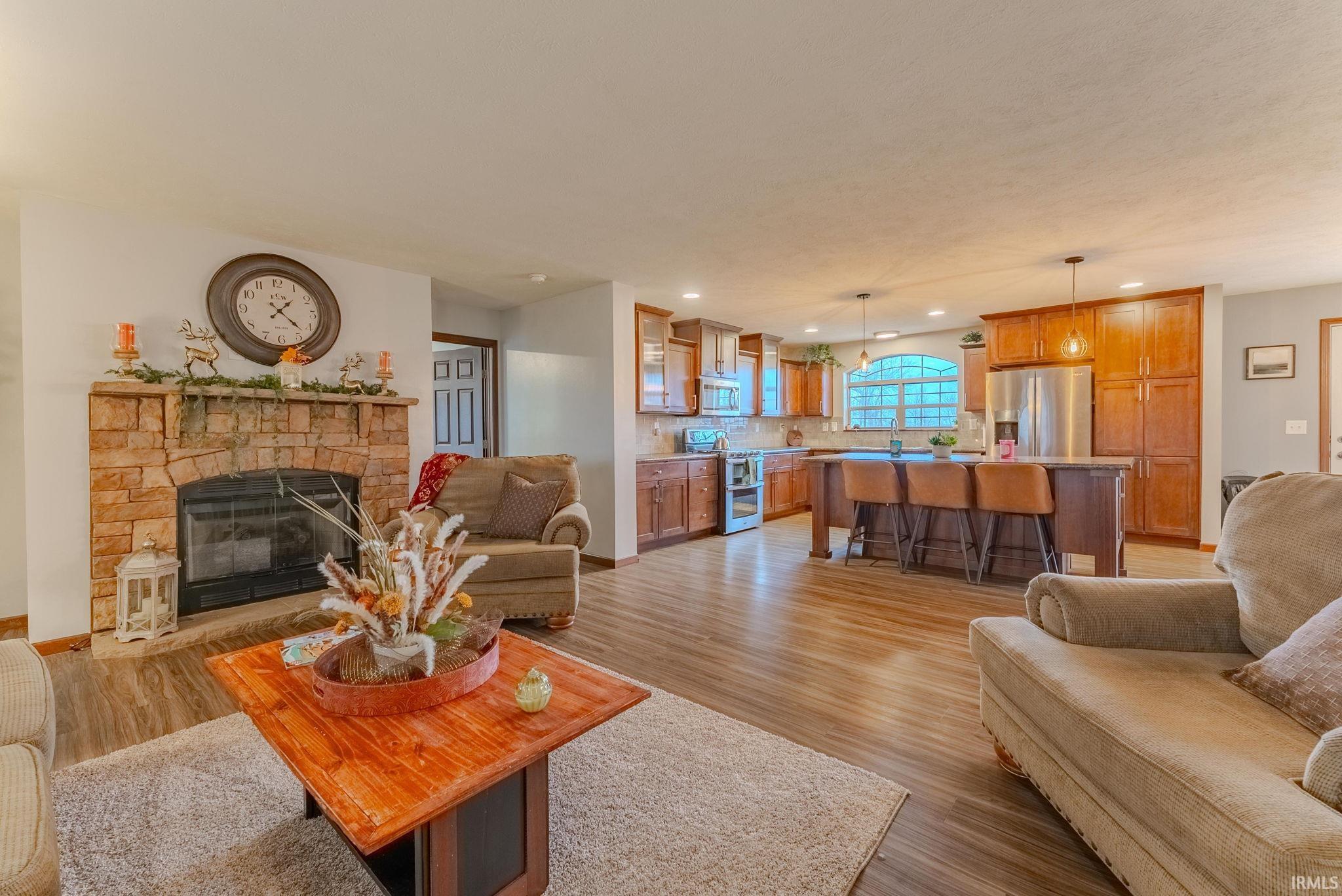 Living area with a stone fireplace, light wood finished floors, and recessed lighting