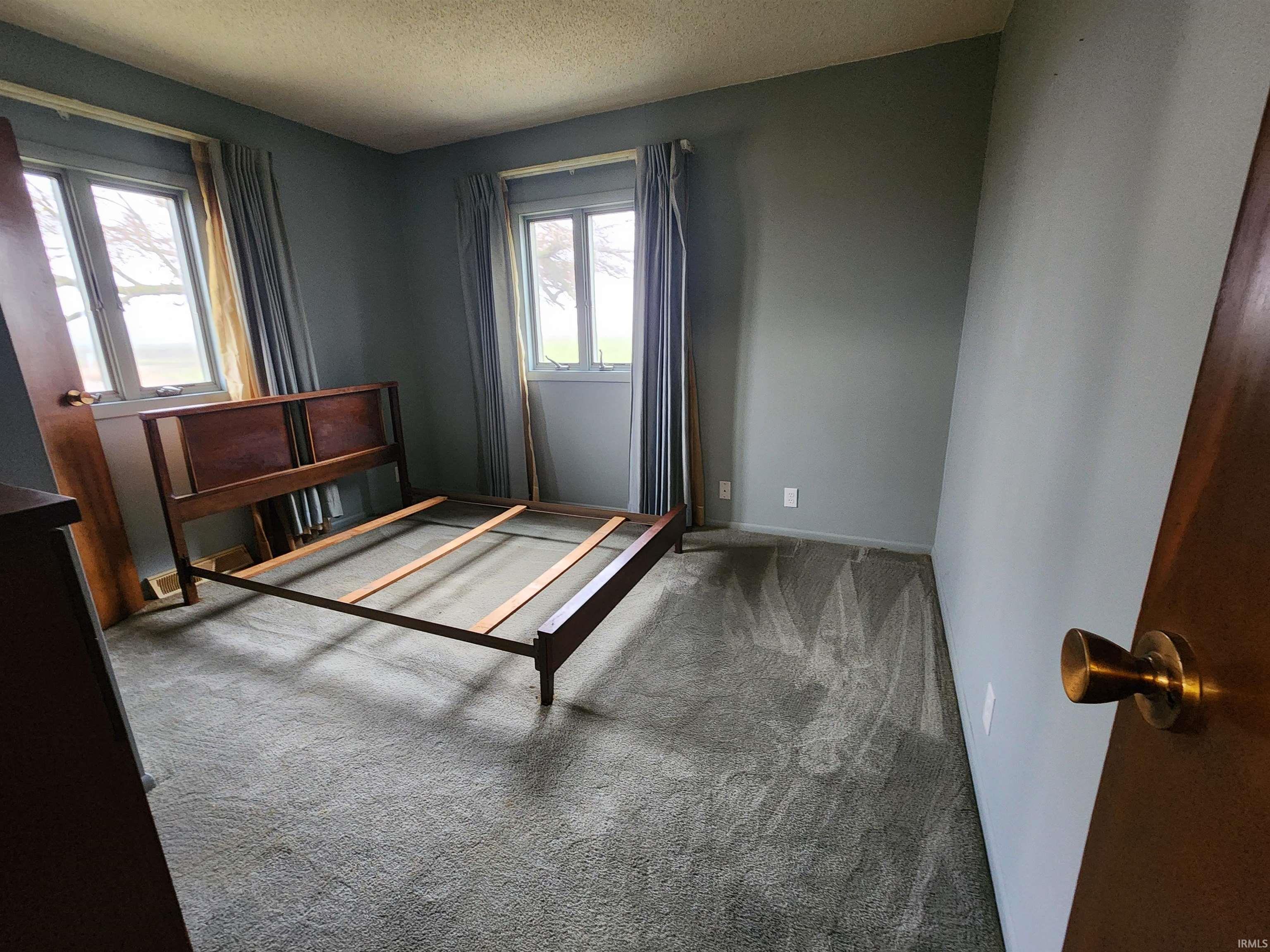 Carpeted bedroom with a textured ceiling and baseboards