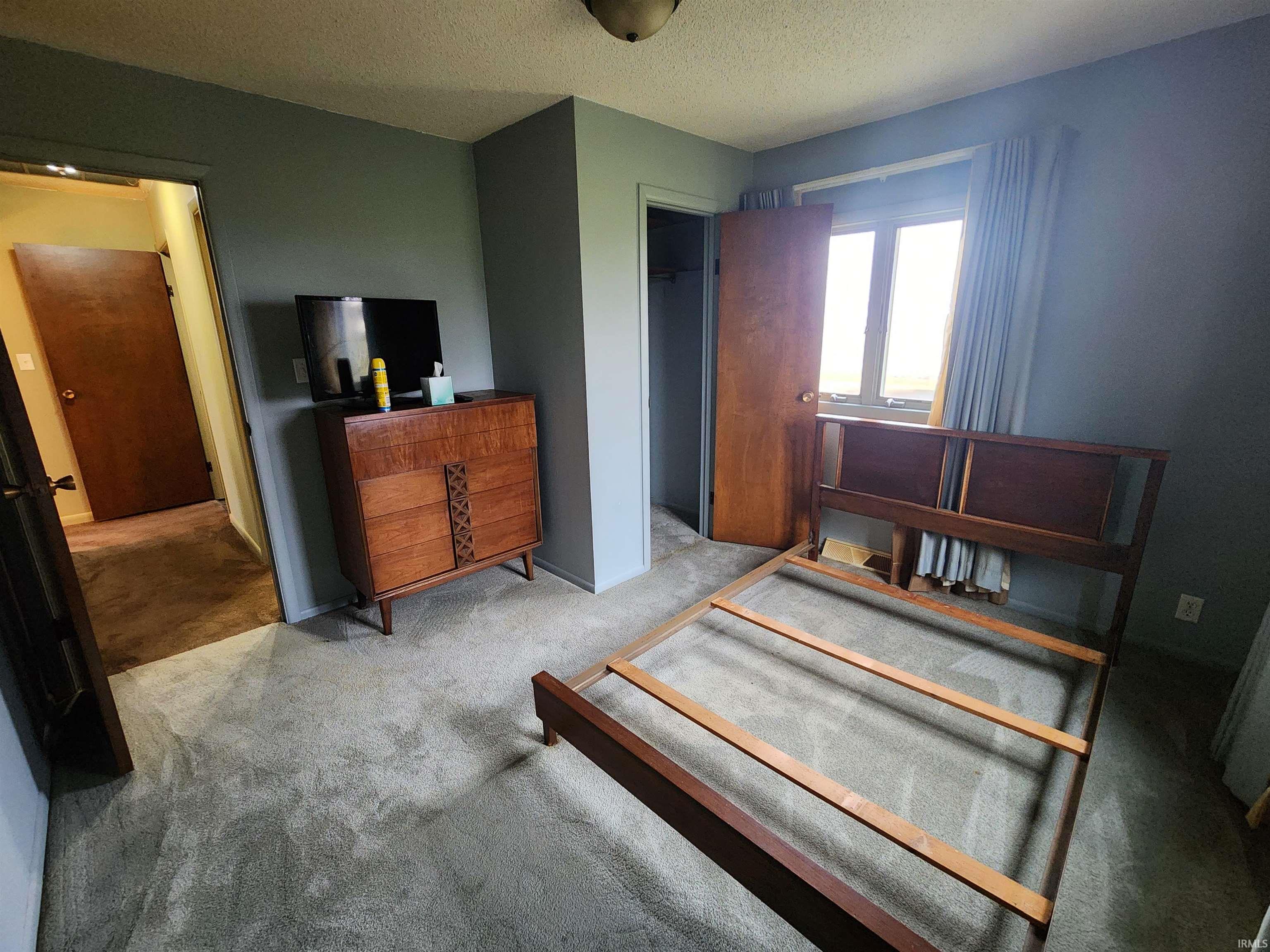 Carpeted bedroom featuring a textured ceiling and a walk in closet