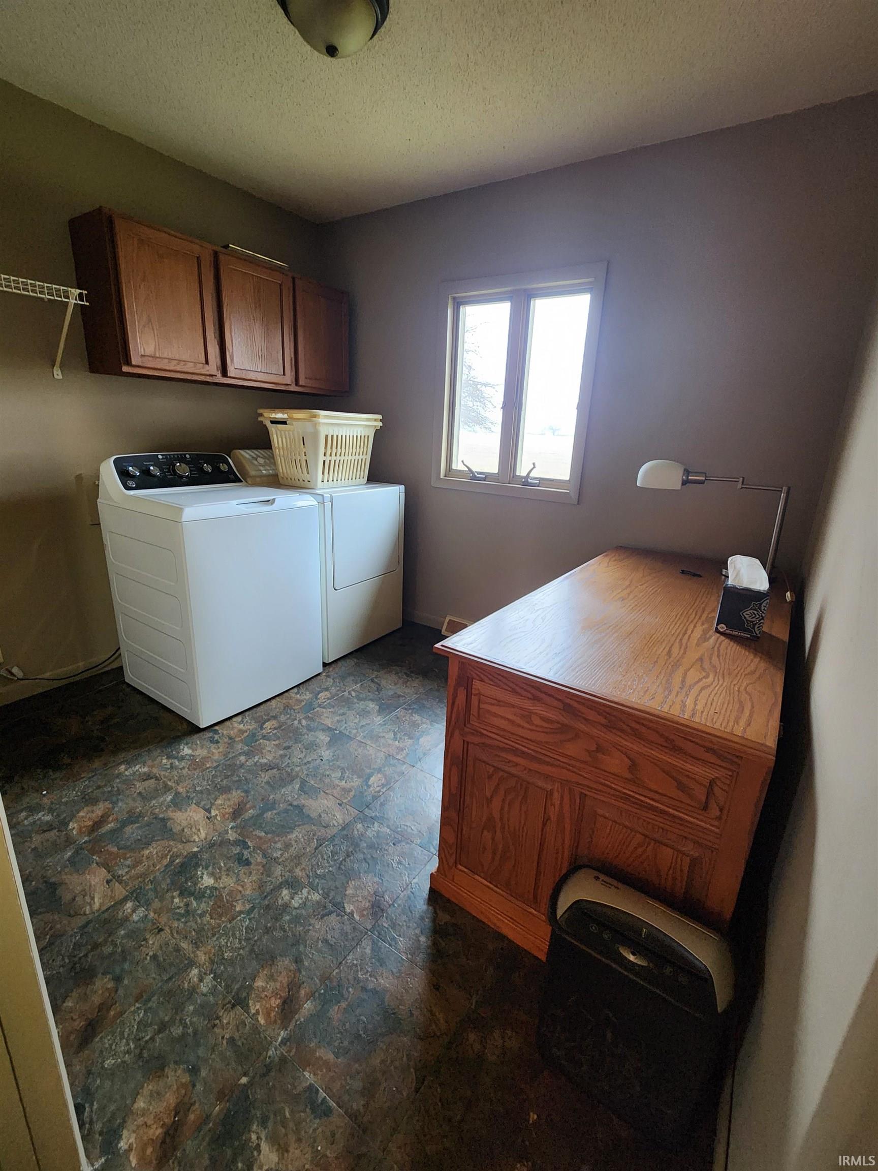 Laundry area with cabinet space, washing machine and dryer, a textured ceiling, and dark floors