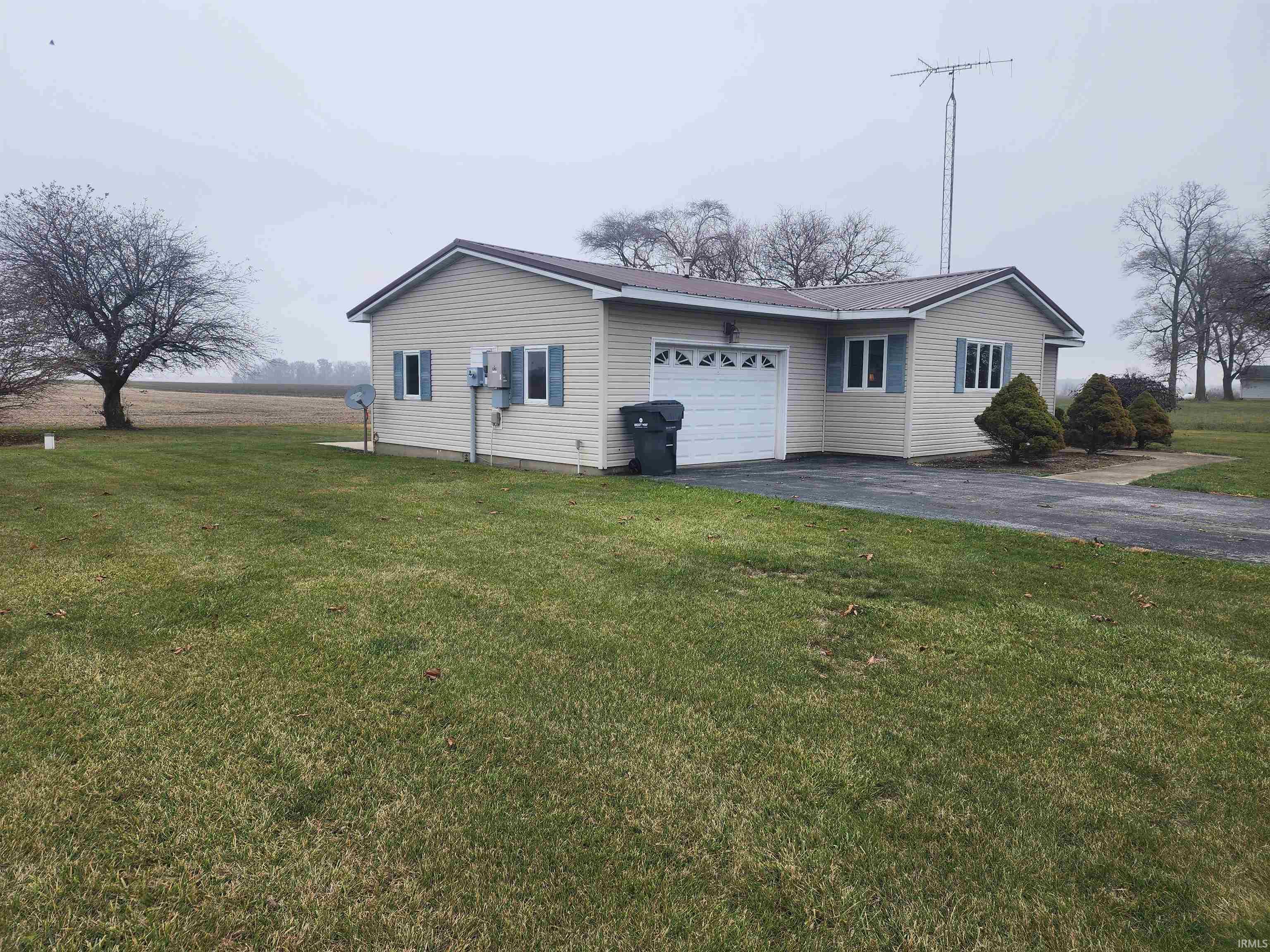 View of side of property with a lawn, a garage, and asphalt driveway