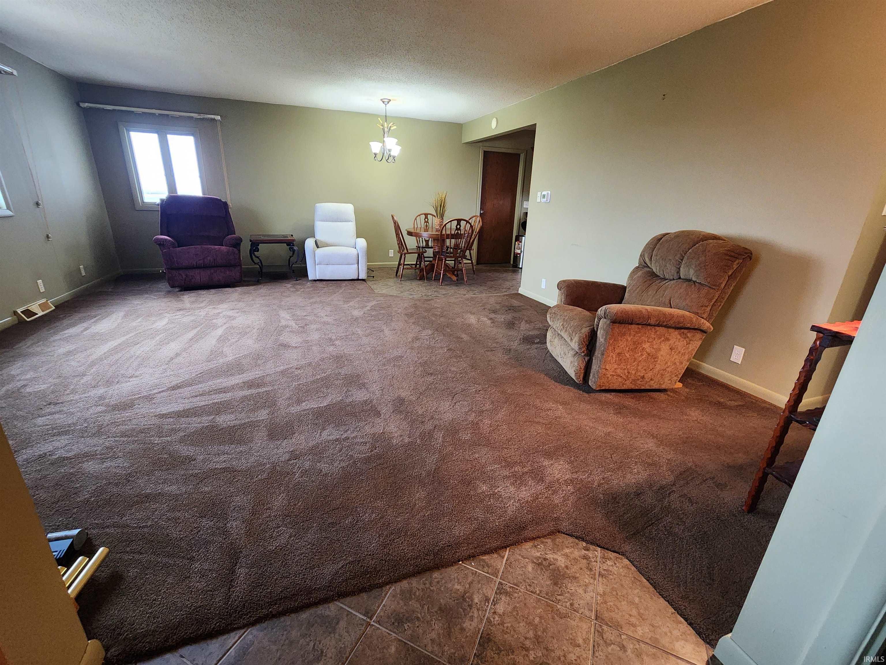 Living area with carpet, a textured ceiling, and a chandelier