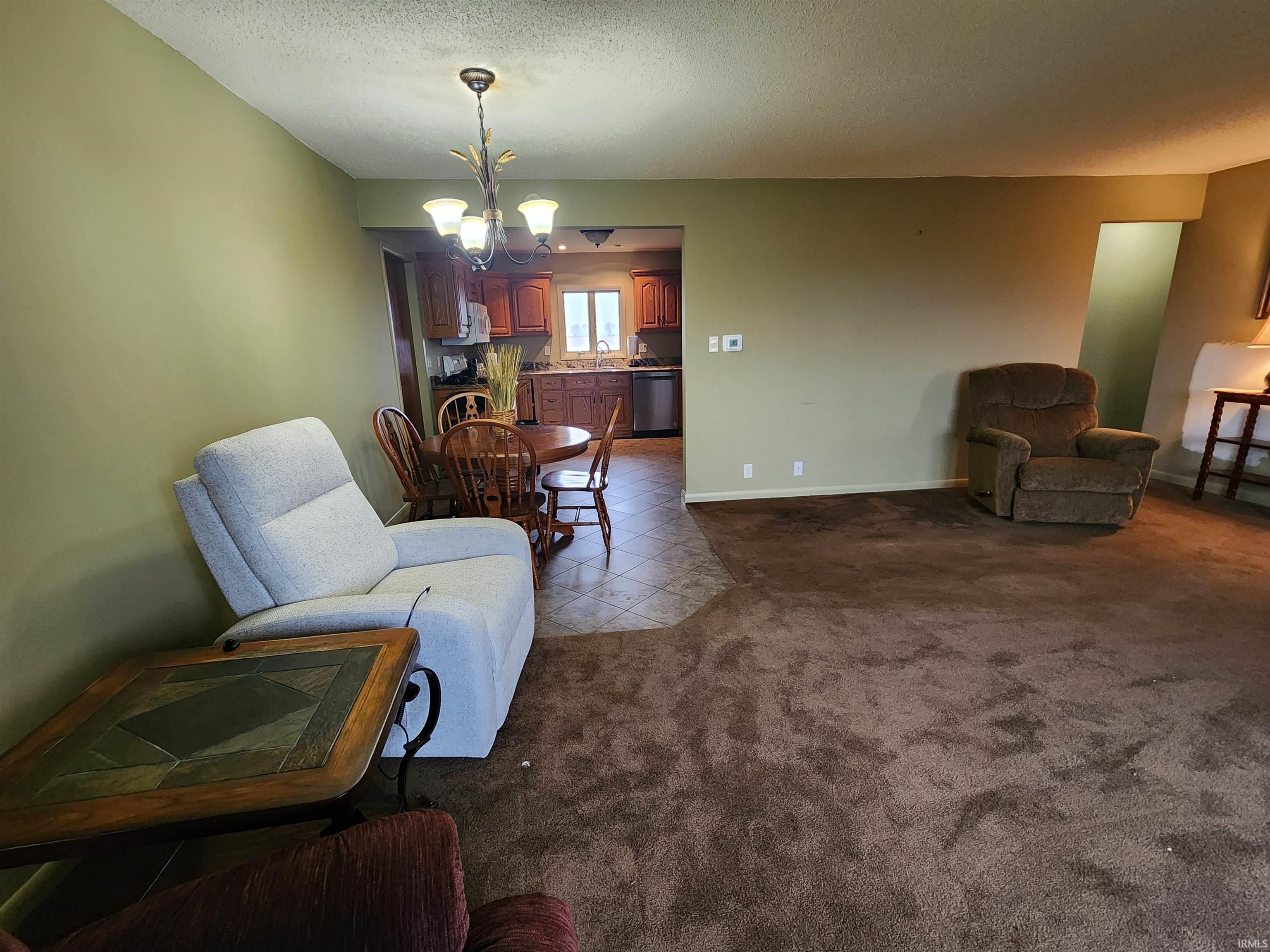 Living area featuring tile patterned floors, a textured ceiling, carpet, and a chandelier
