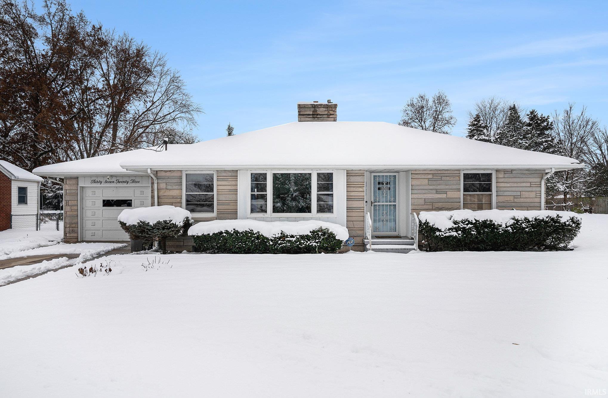 Single story home with a chimney, stone siding, and a garage