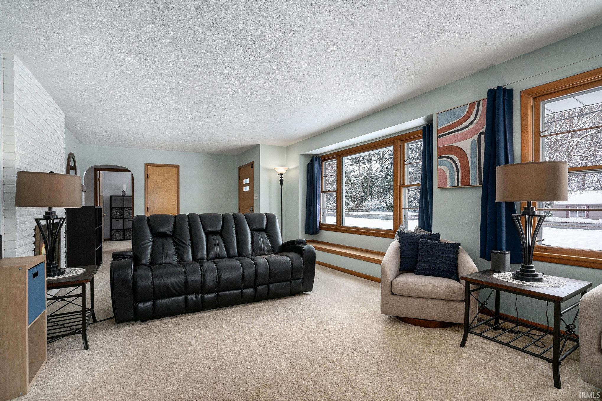 Carpeted living area featuring a textured ceiling and arched walkways