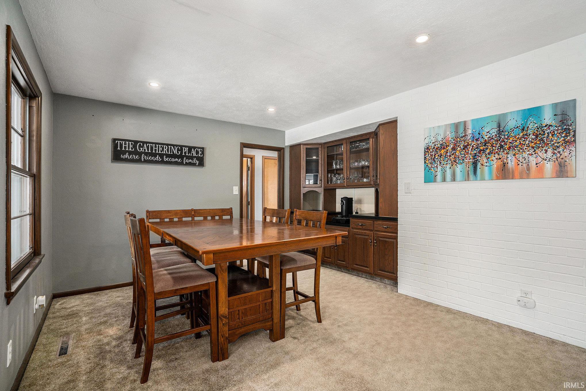 Dining area with light colored carpet and recessed lighting