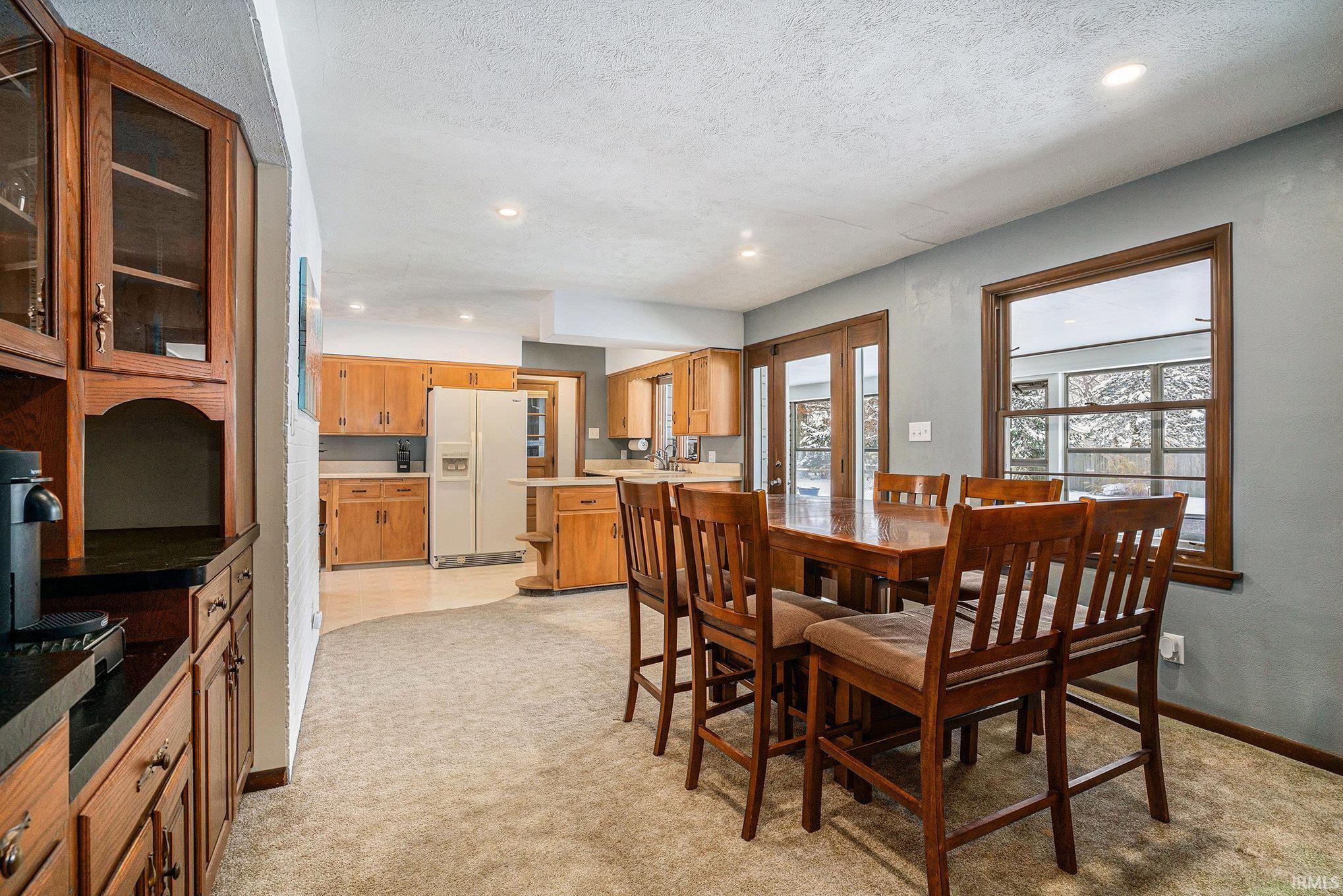 Dining room with light carpet, recessed lighting, and a textured ceiling