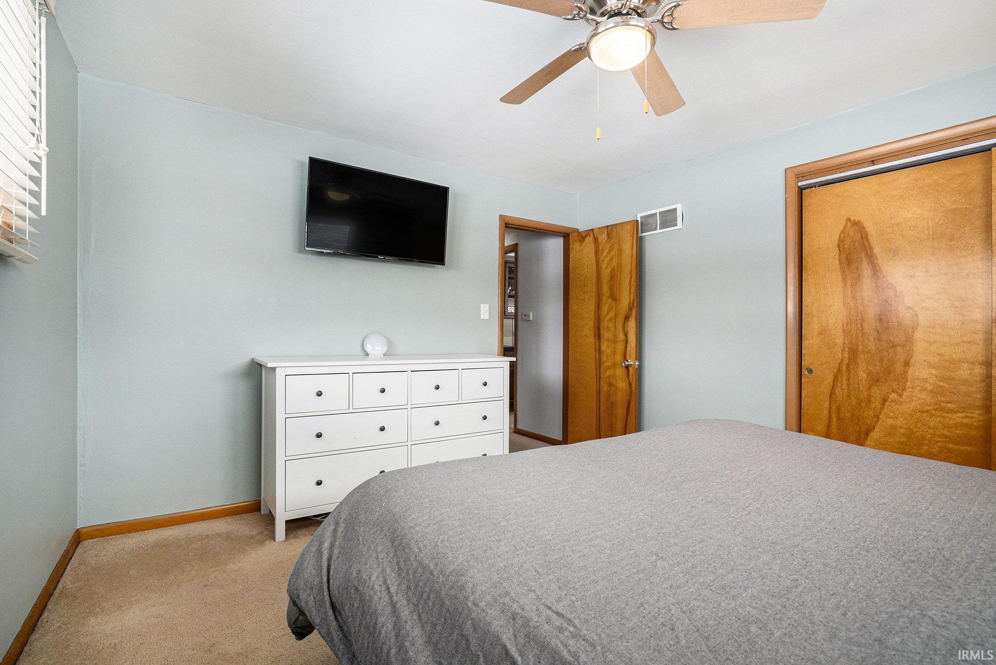 Bedroom featuring ceiling fan, light carpet, and a closet