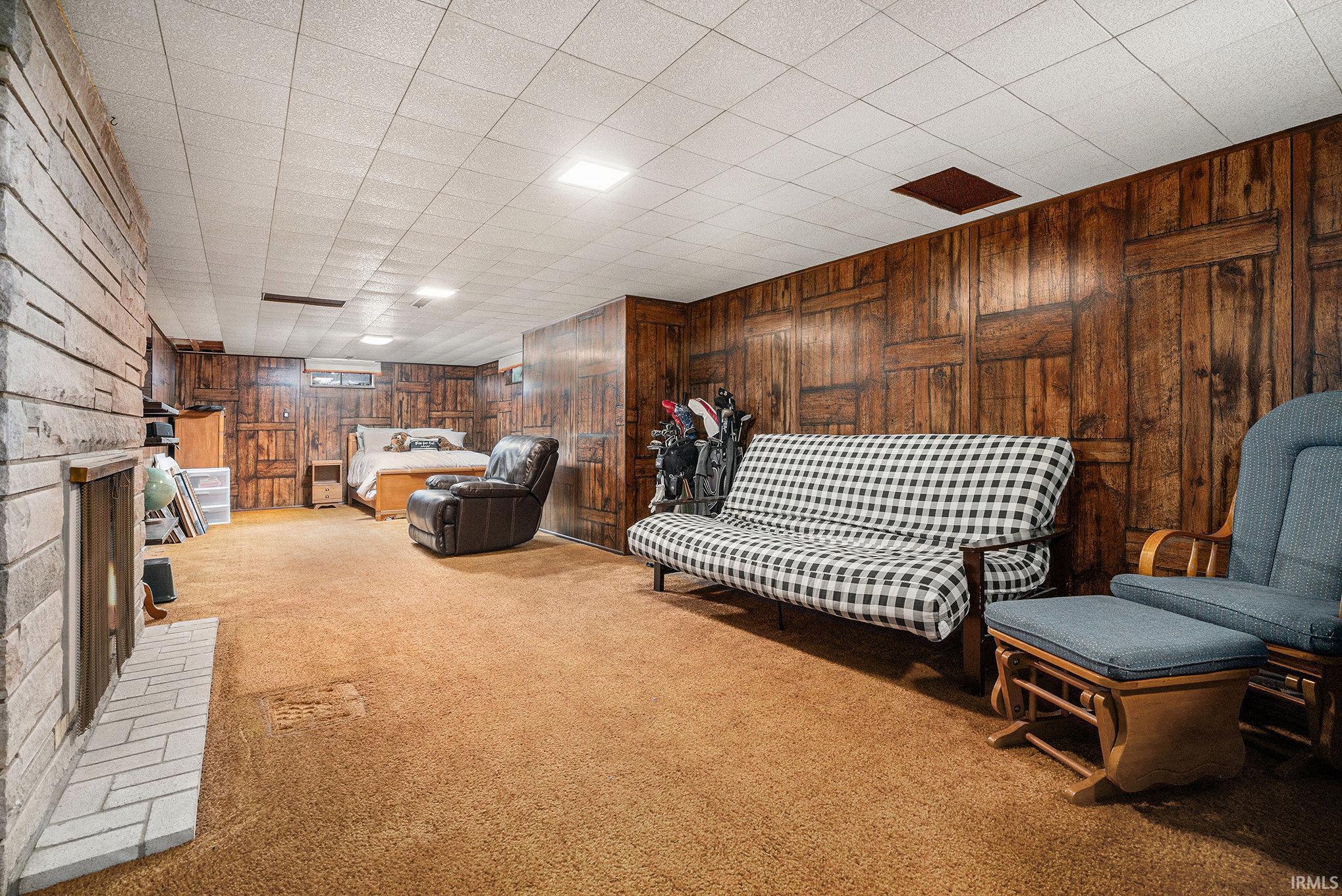 Living area with carpet flooring, wooden walls, and a fireplace