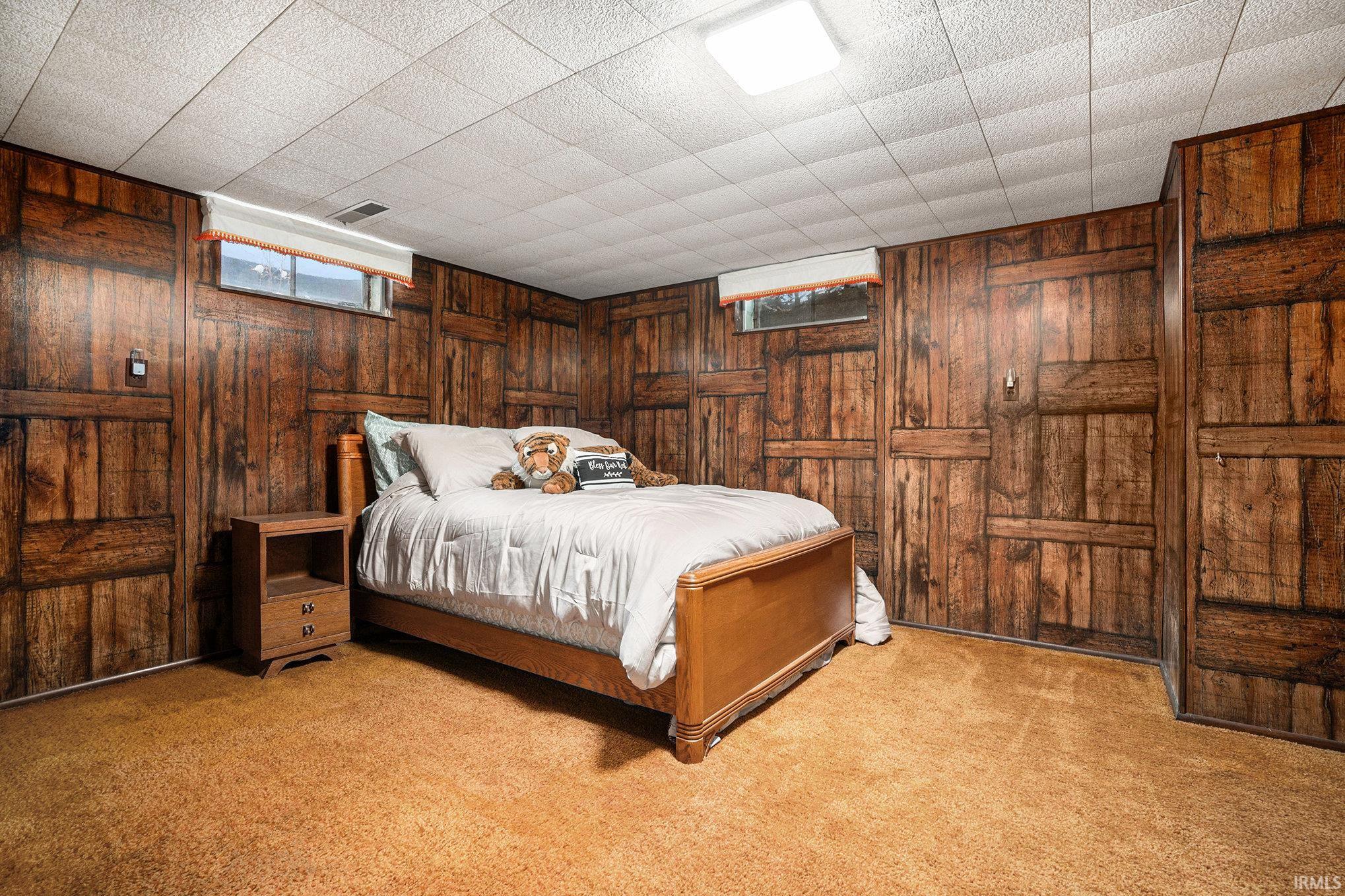 Carpeted bedroom featuring wood walls