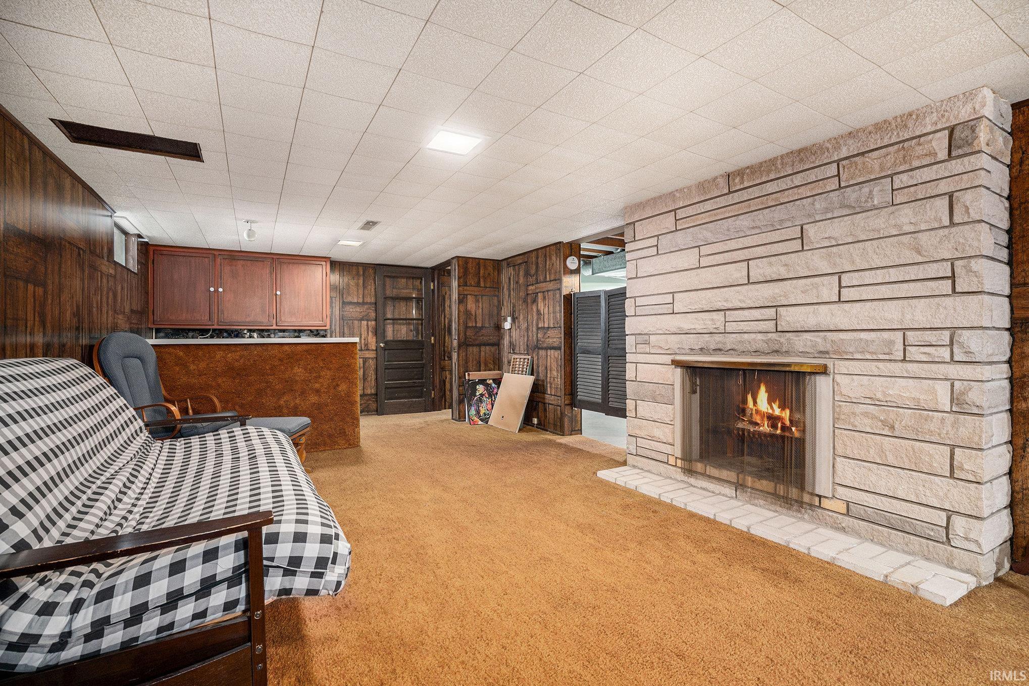 Living area with a fireplace, wood walls, and light colored carpet