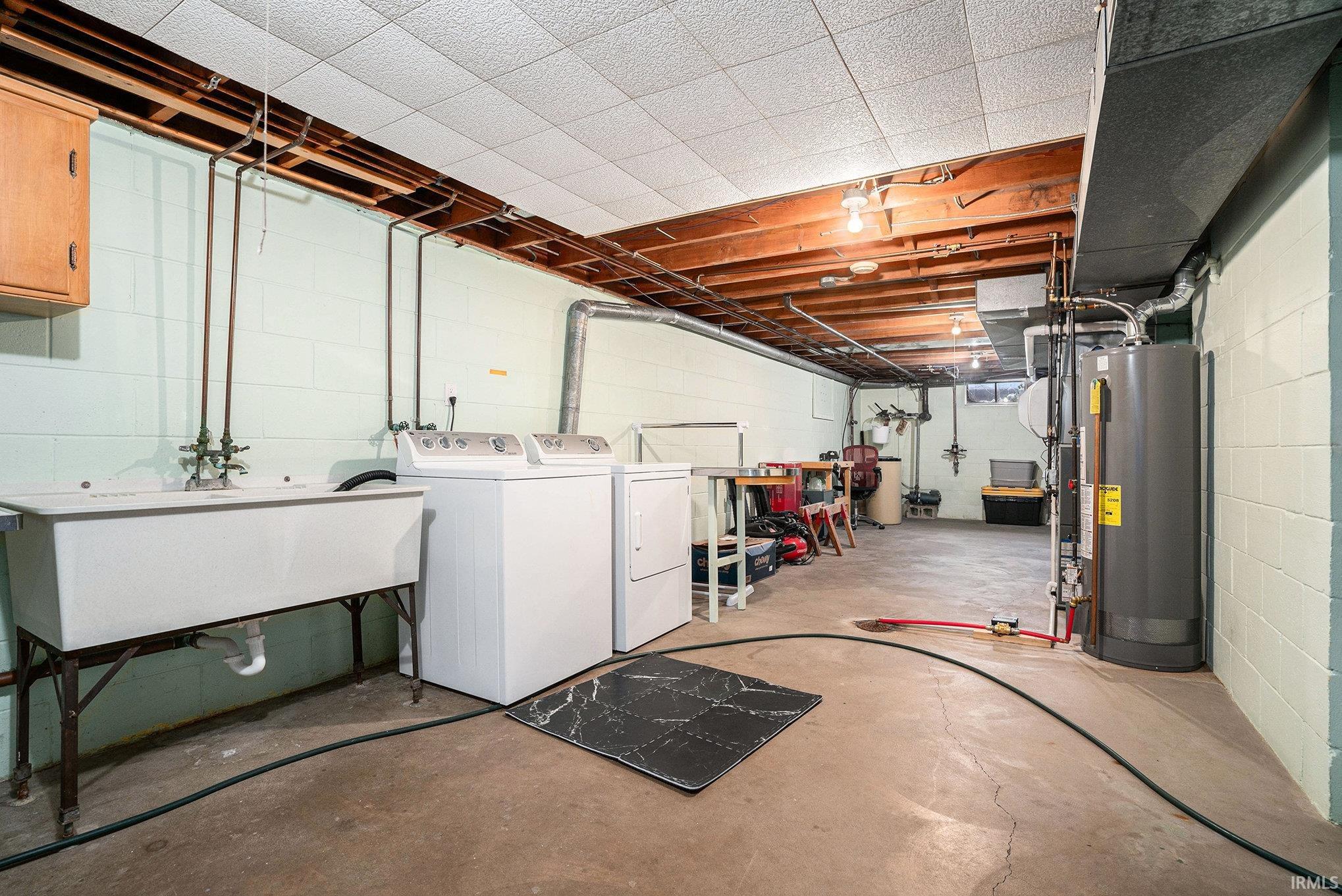 Unfinished below grade area featuring gas water heater and washer and dryer
