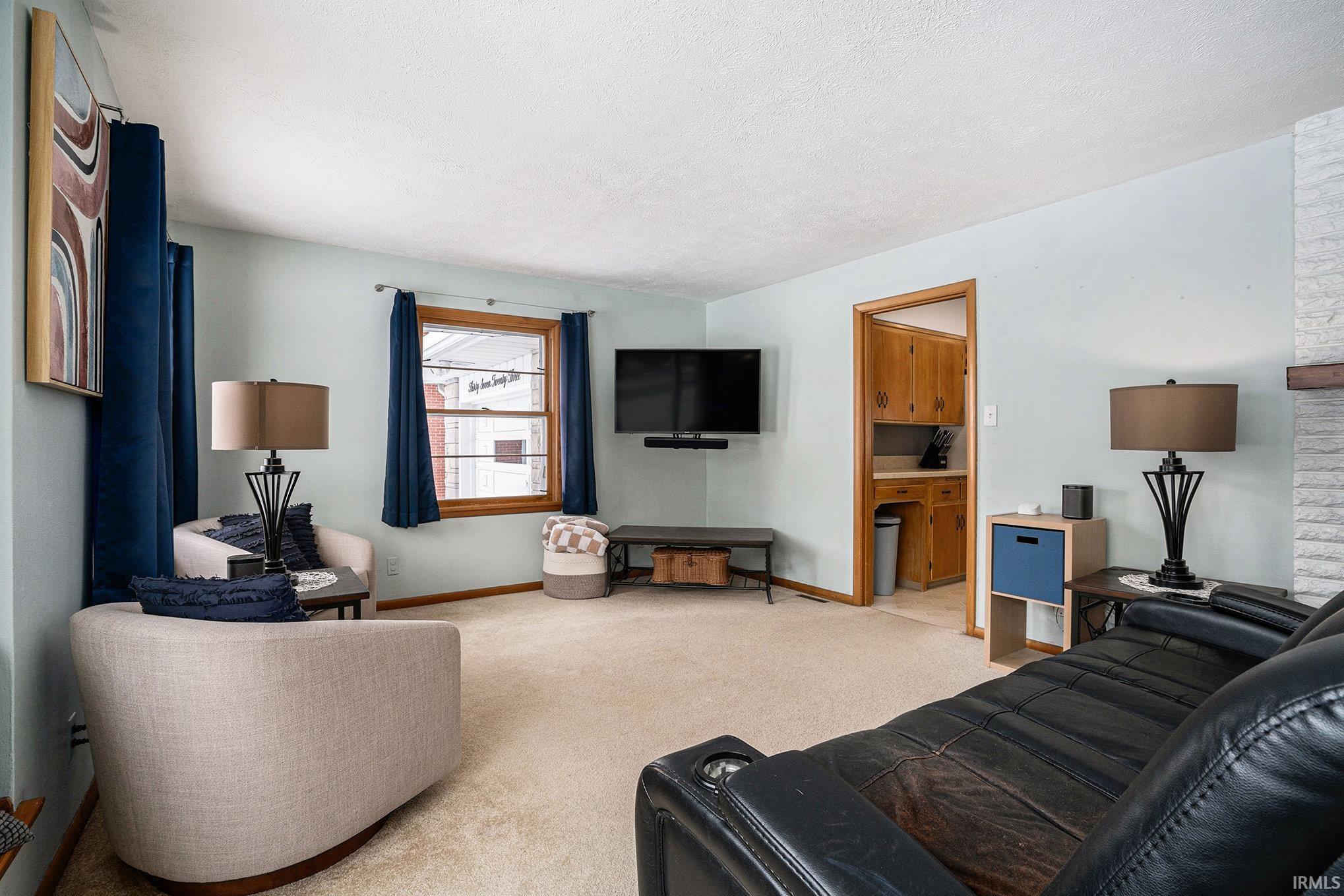 Living area with light carpet and a textured ceiling