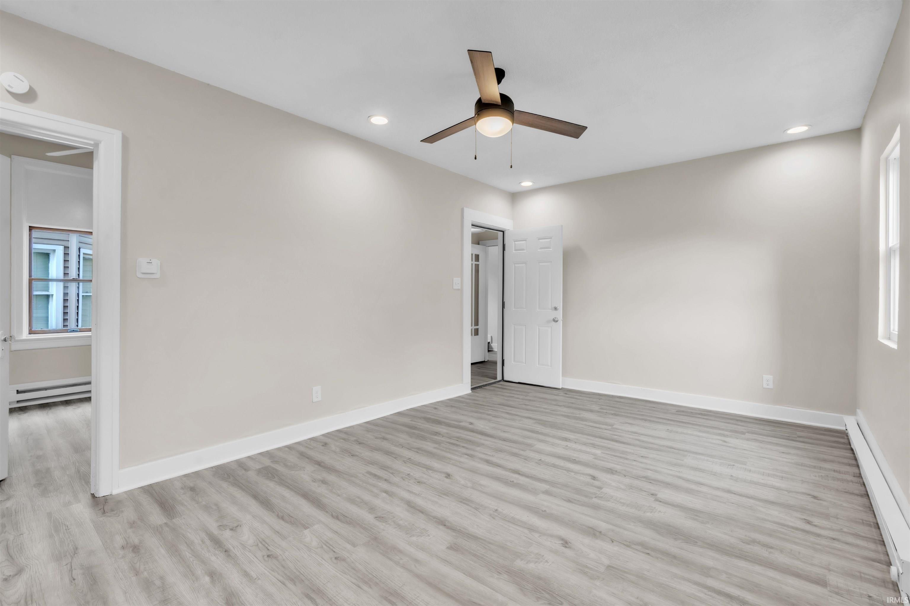 Unfurnished room featuring a baseboard radiator, light wood-style floors, recessed lighting, ceiling fan, and a baseboard heating unit