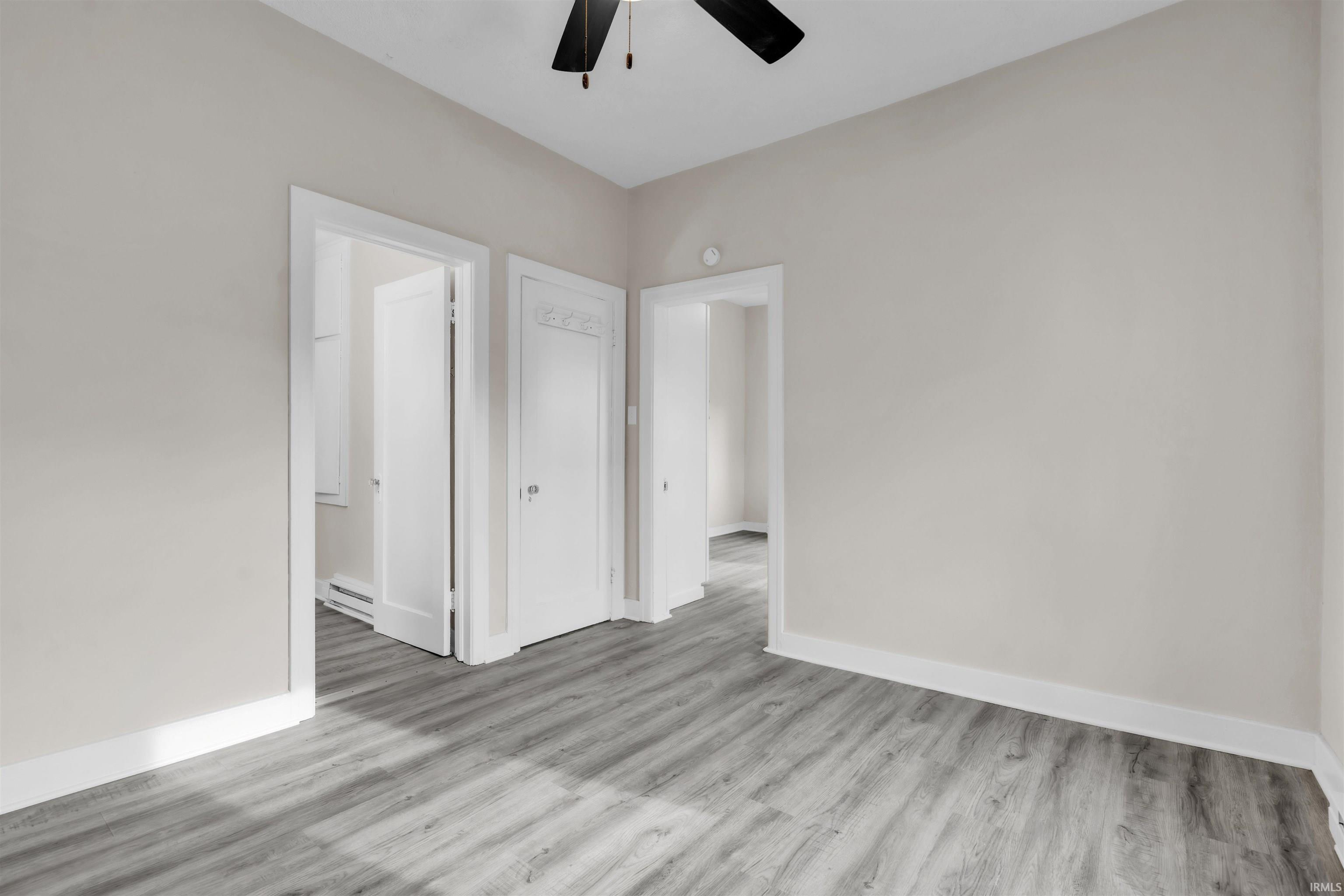 Unfurnished bedroom with light wood-style floors, baseboard heating, and ceiling fan