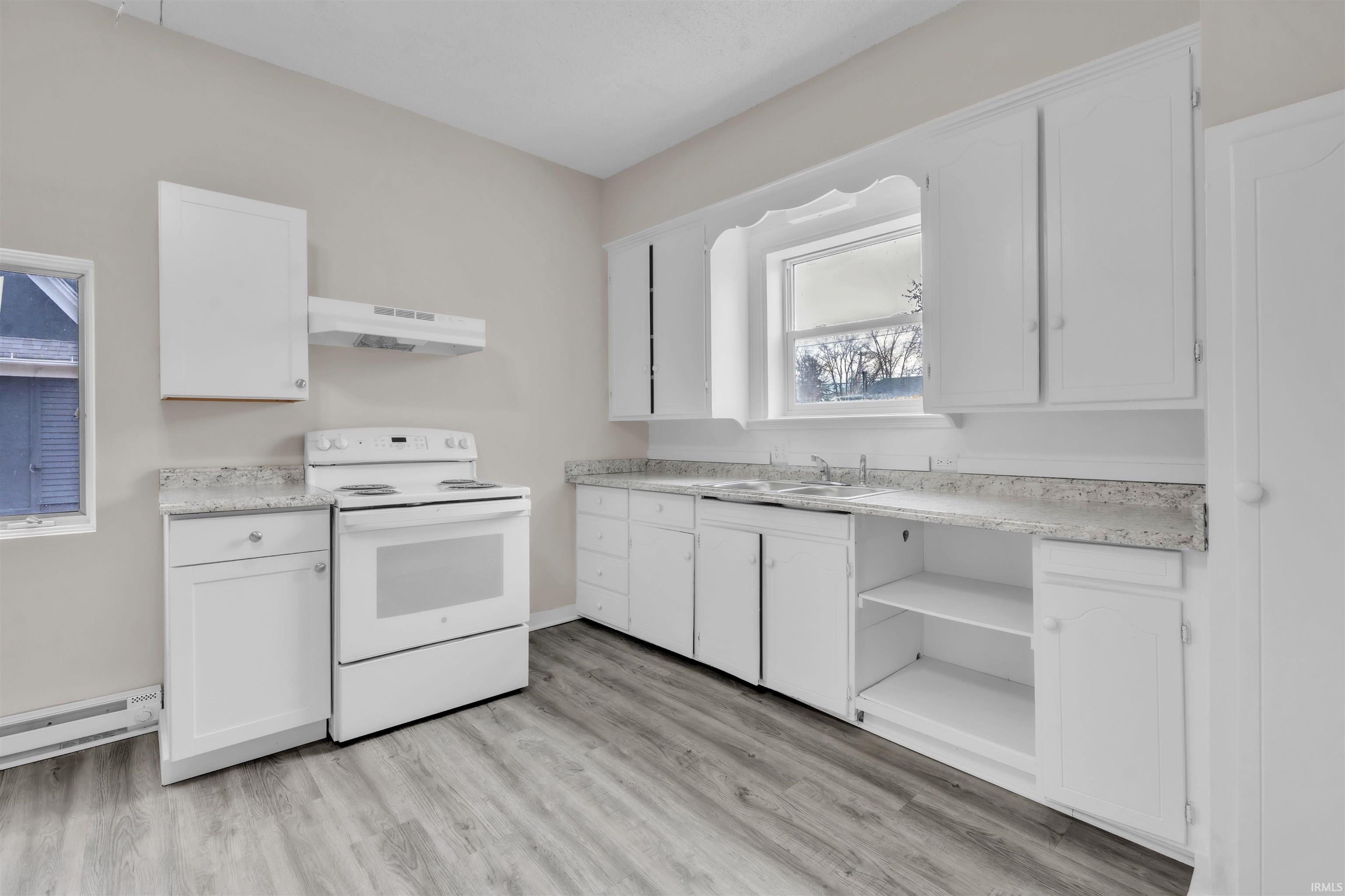 Kitchen featuring white range with electric stovetop, white cabinets, and light countertops