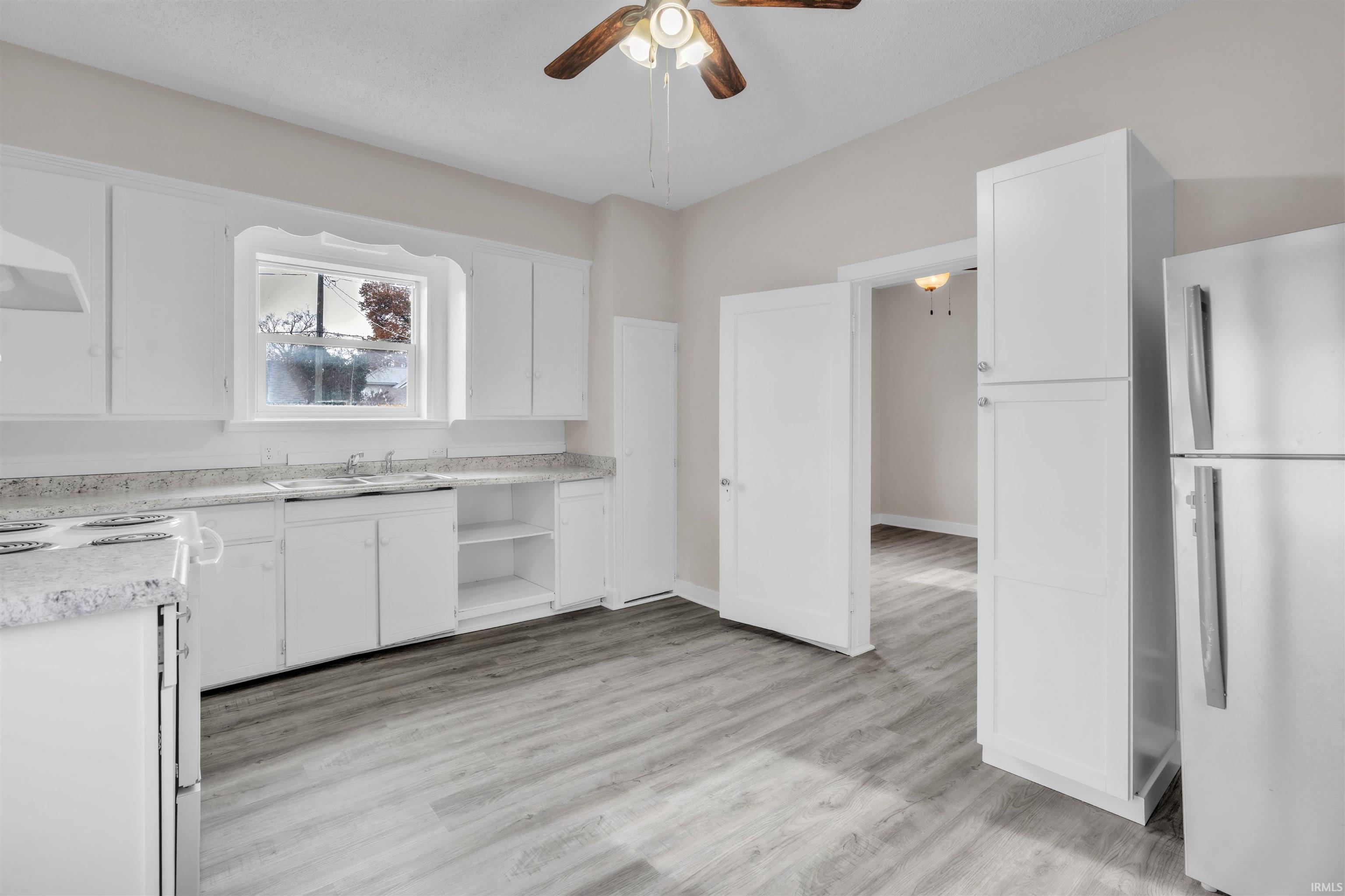 Kitchen featuring freestanding refrigerator, open shelves, white range with electric stovetop, white cabinets, and light countertops