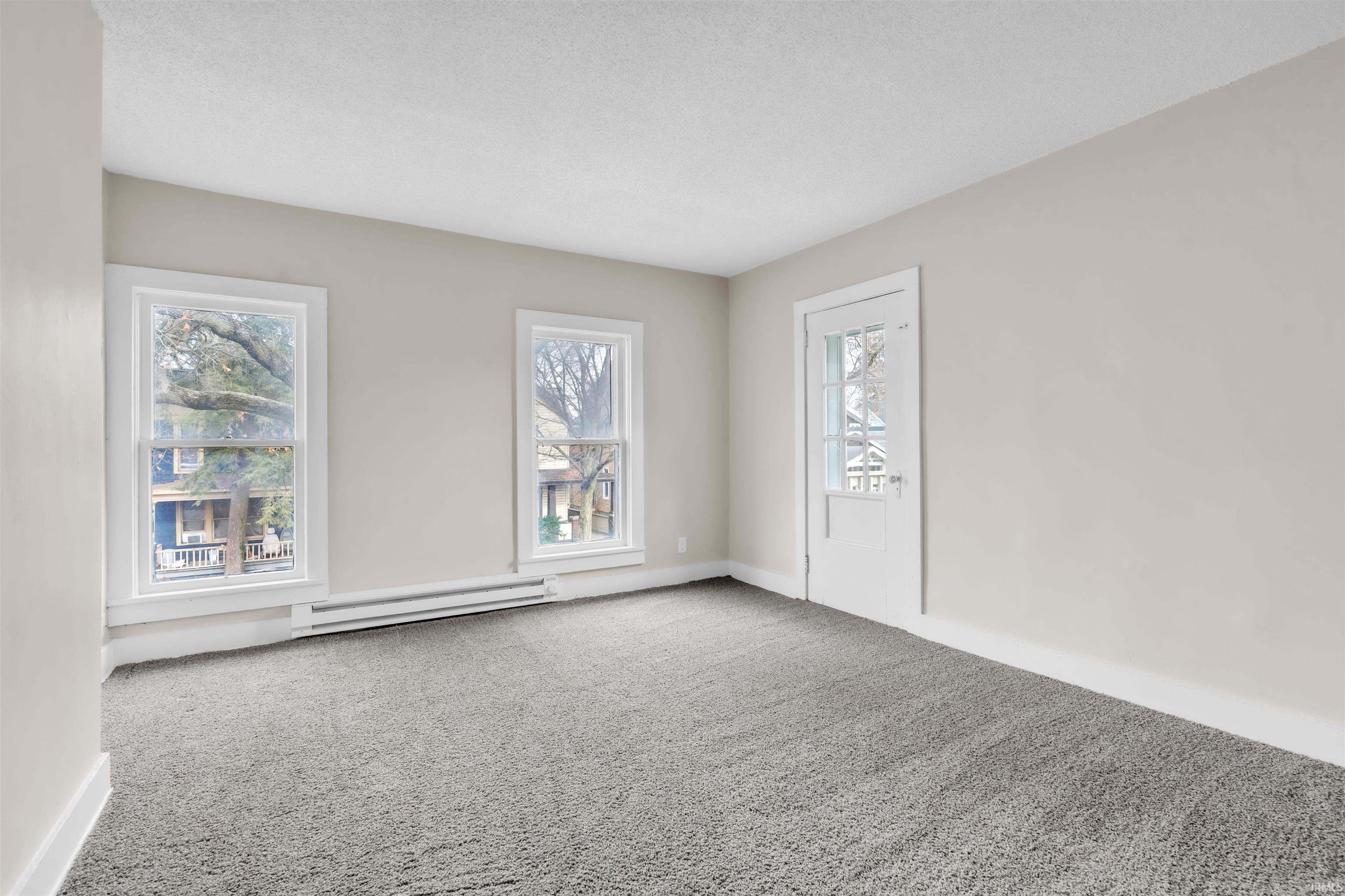 Carpeted empty room with a baseboard heating unit and a textured ceiling