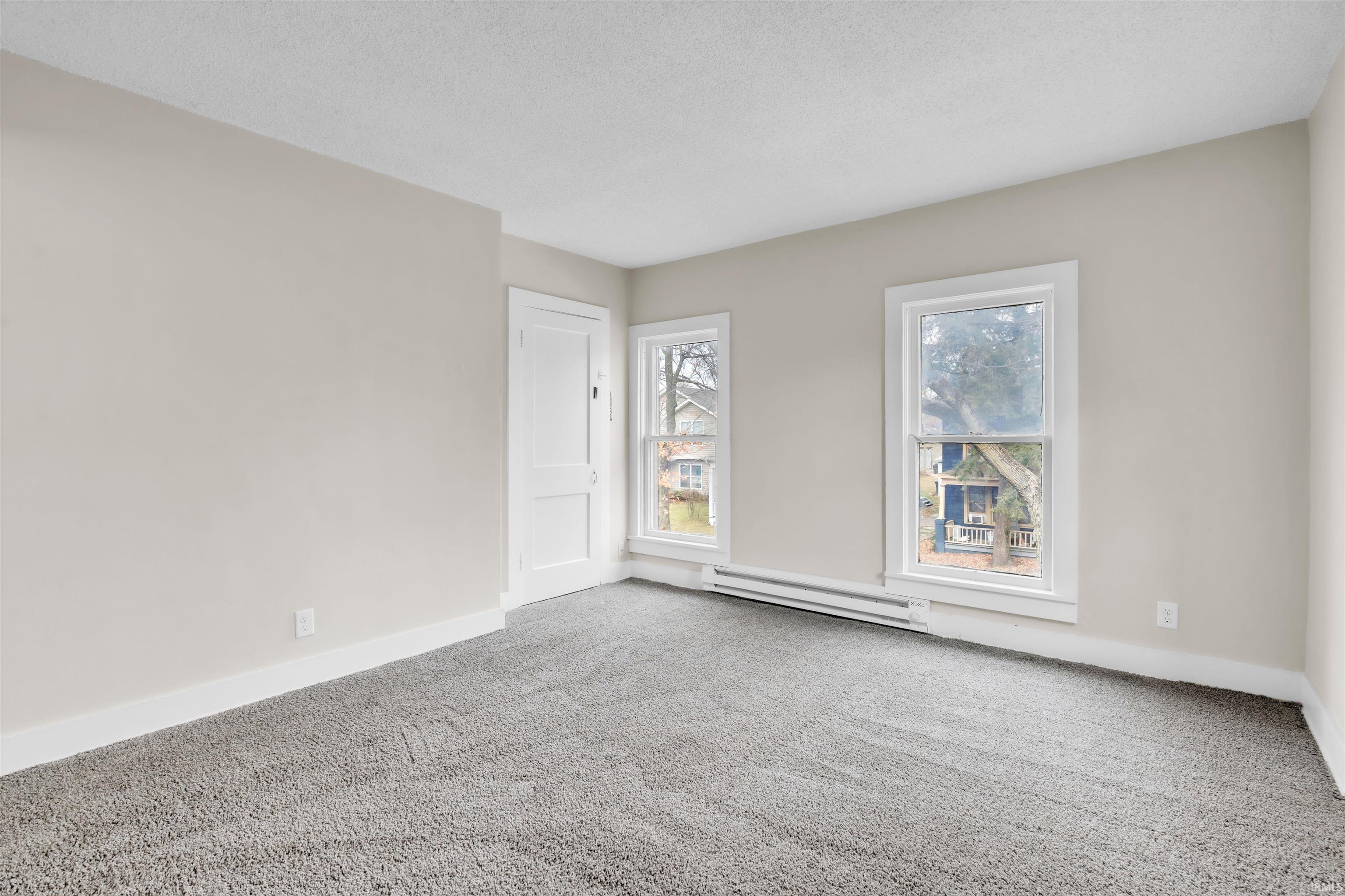 Carpeted spare room with a baseboard radiator and a textured ceiling