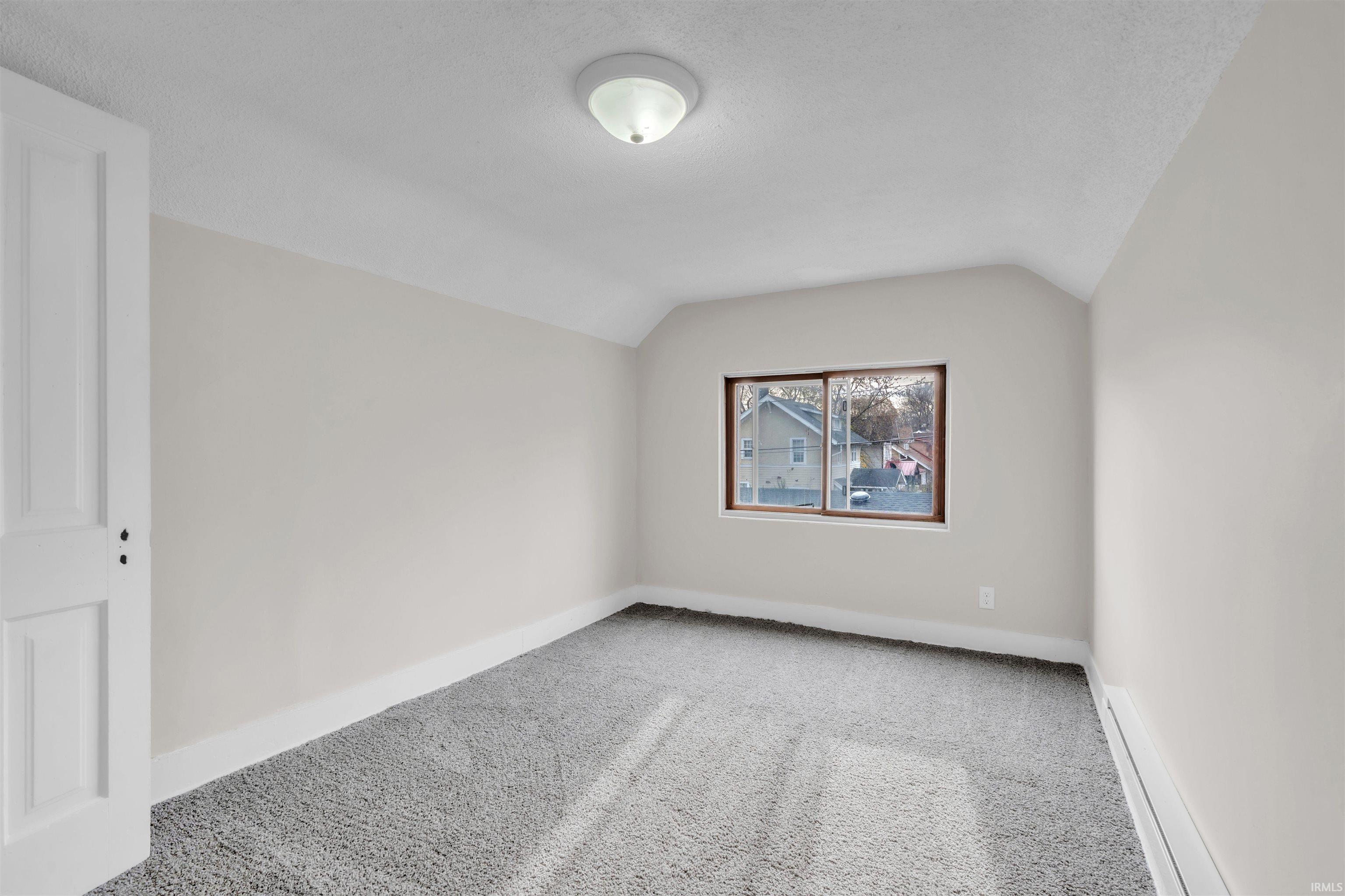 Additional living space featuring carpet, vaulted ceiling, a textured ceiling, and a baseboard heating unit