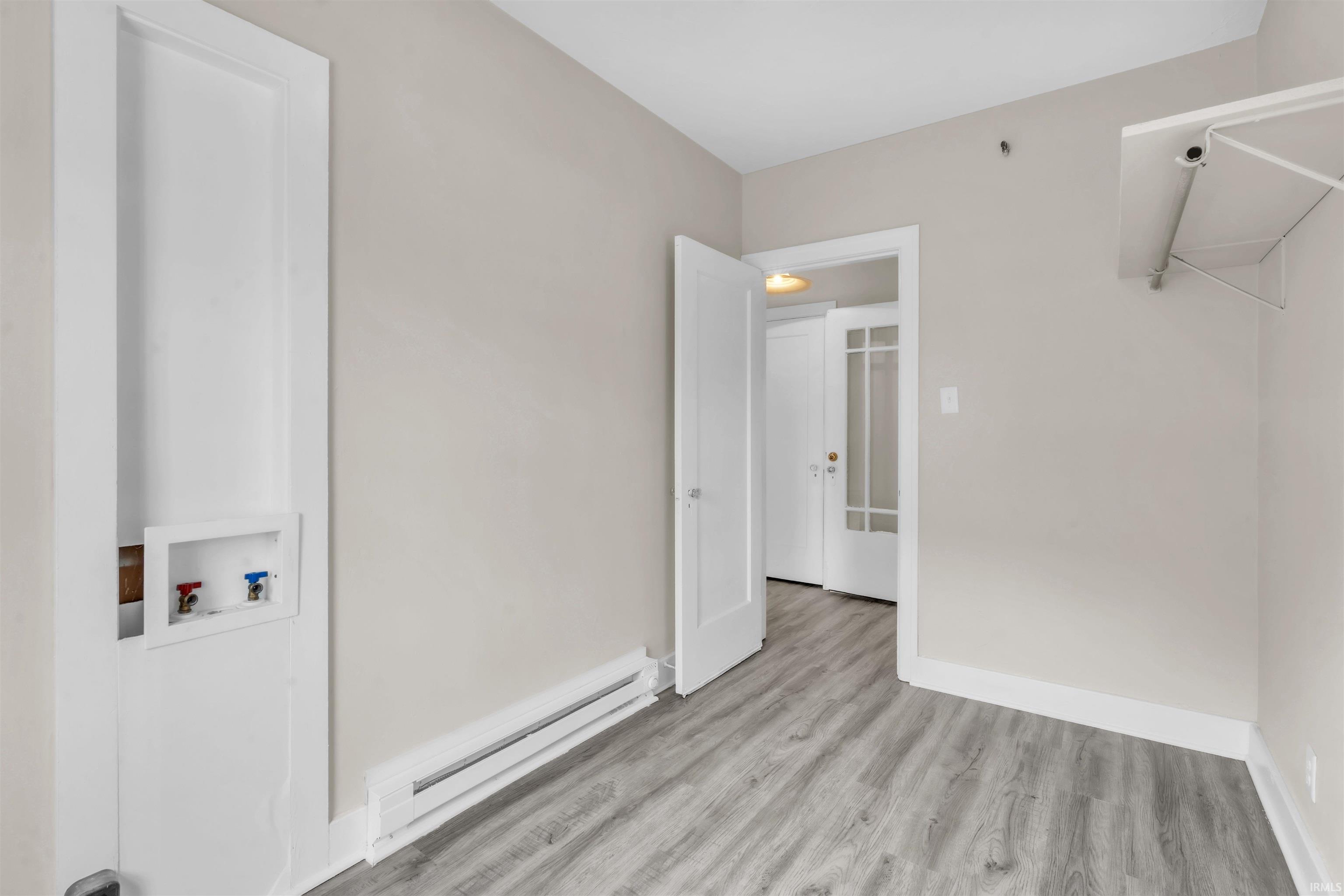 Washroom with baseboard heating, washer hookup, and wood finished floors