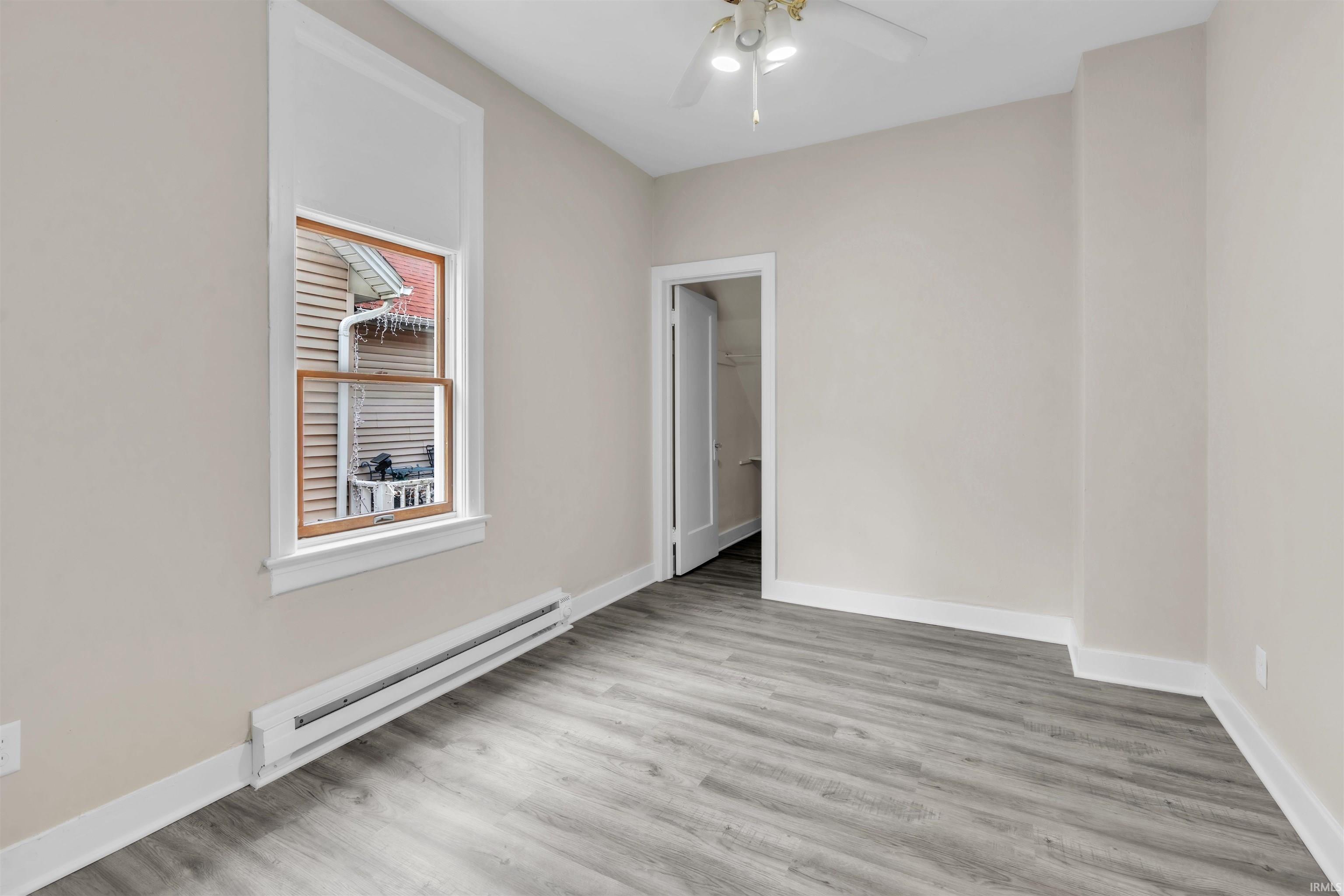 Empty room featuring baseboard heating, light wood finished floors, and a ceiling fan