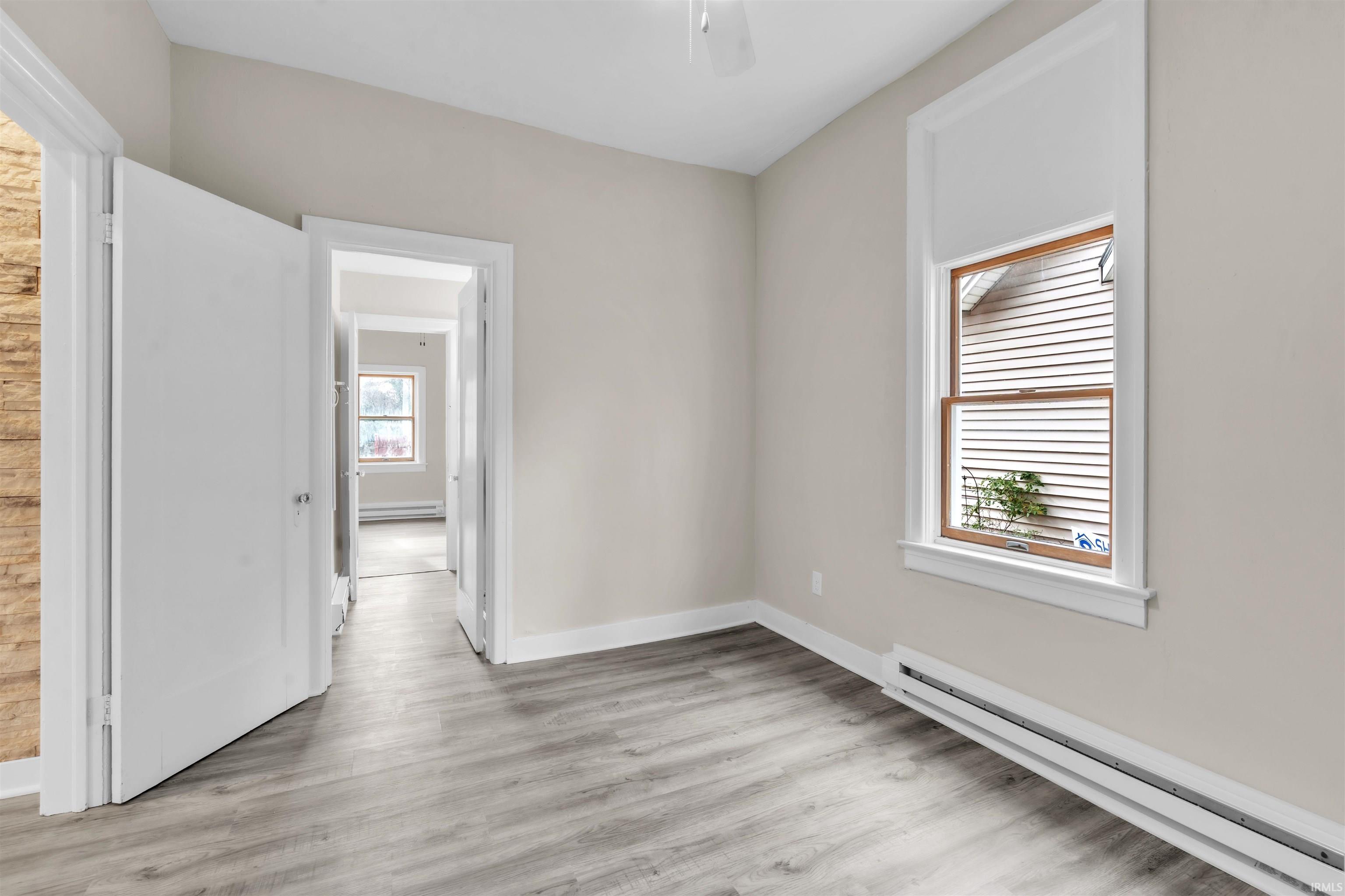 Empty room with baseboard heating and light wood-type flooring