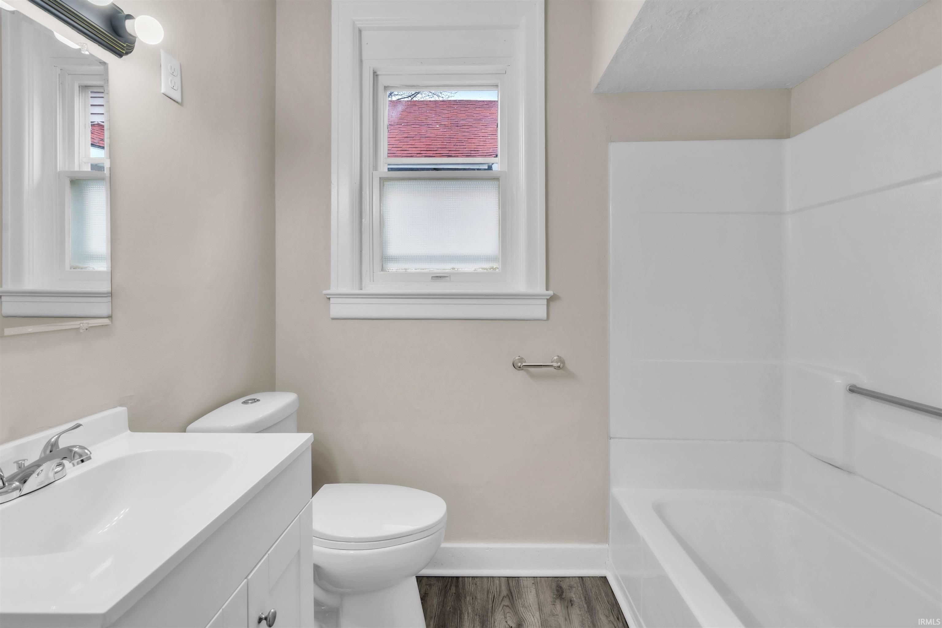 Full bathroom featuring vanity, dark wood-type flooring, and tub / shower combination